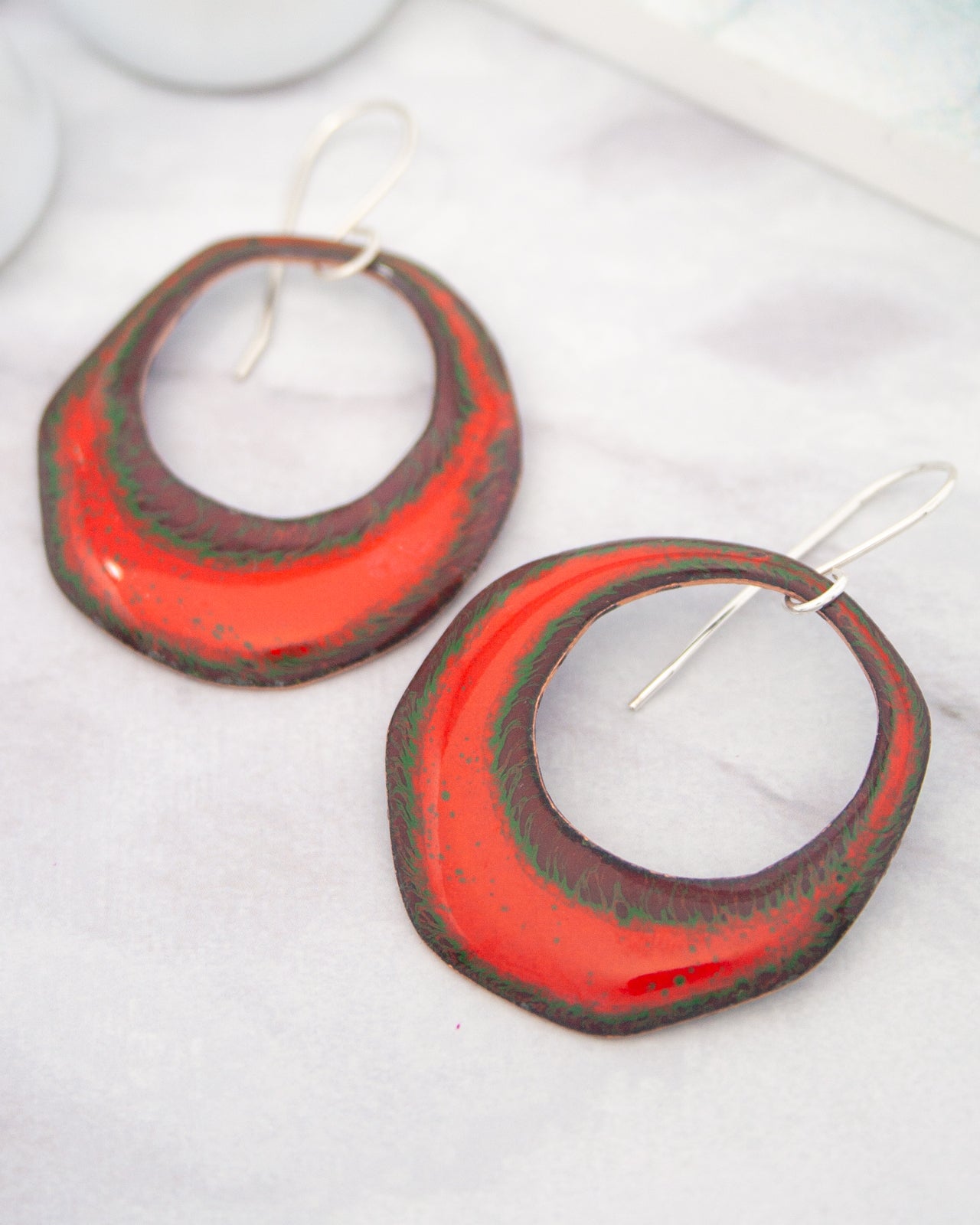 A pair of red and green earrings with a unique, textured design.