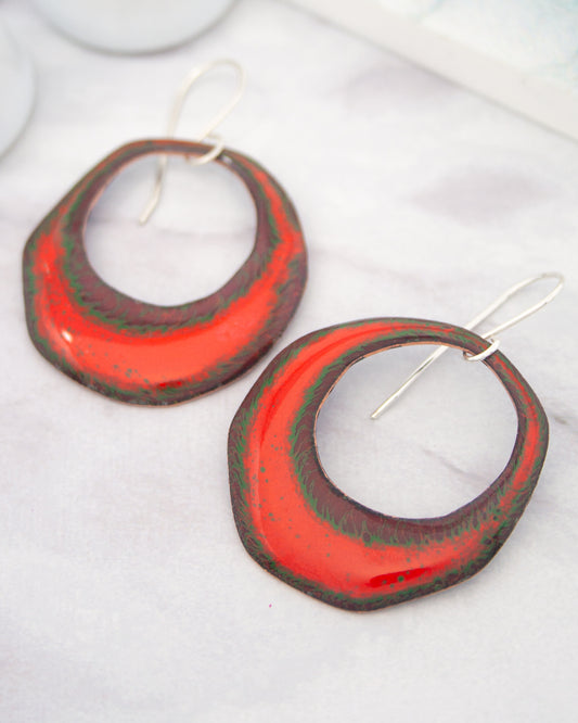 A pair of red and green earrings with a unique, textured design.
