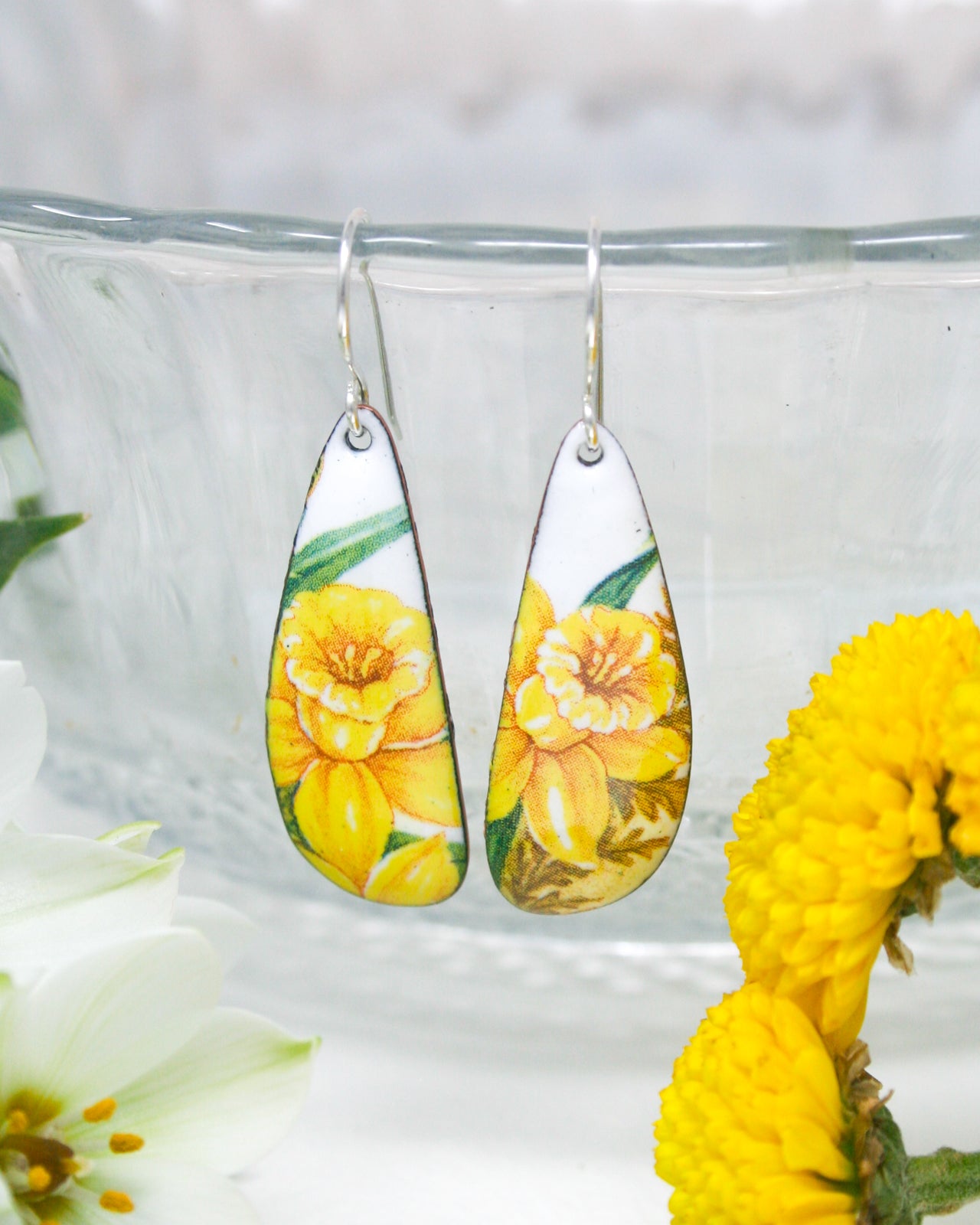 a pair of earrings with yellow flowers painted on them