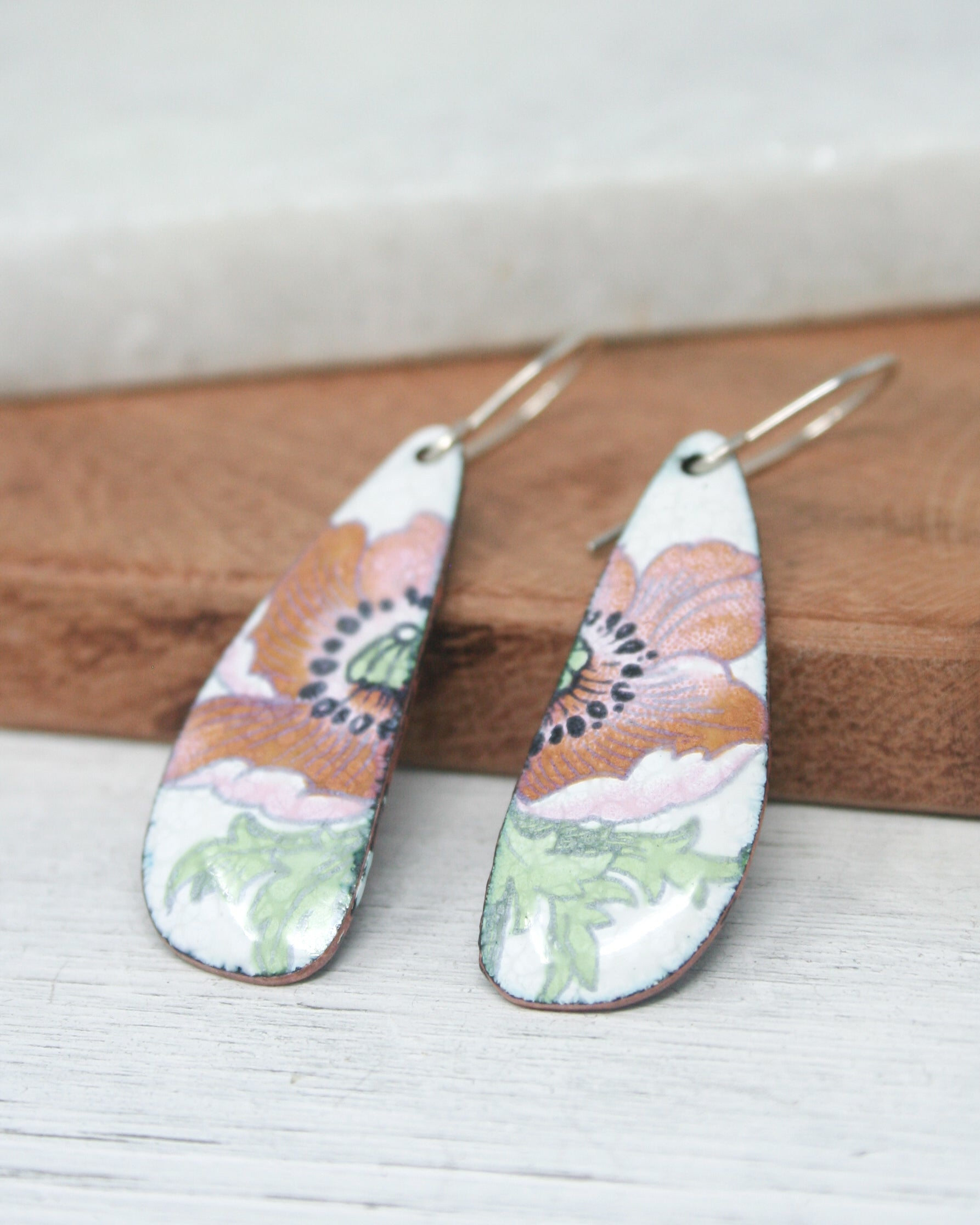 a pair of earrings sitting on top of a wooden board