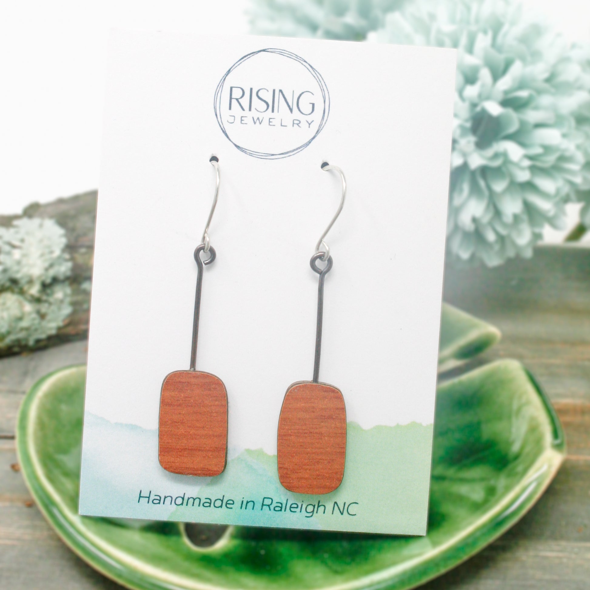 a pair of wooden earrings sitting on top of a green plate