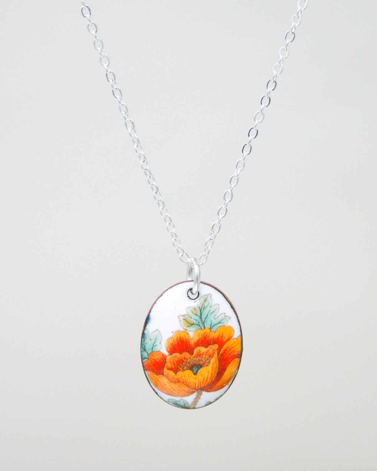 A silver necklace with a pendant featuring a colorful floral design.
