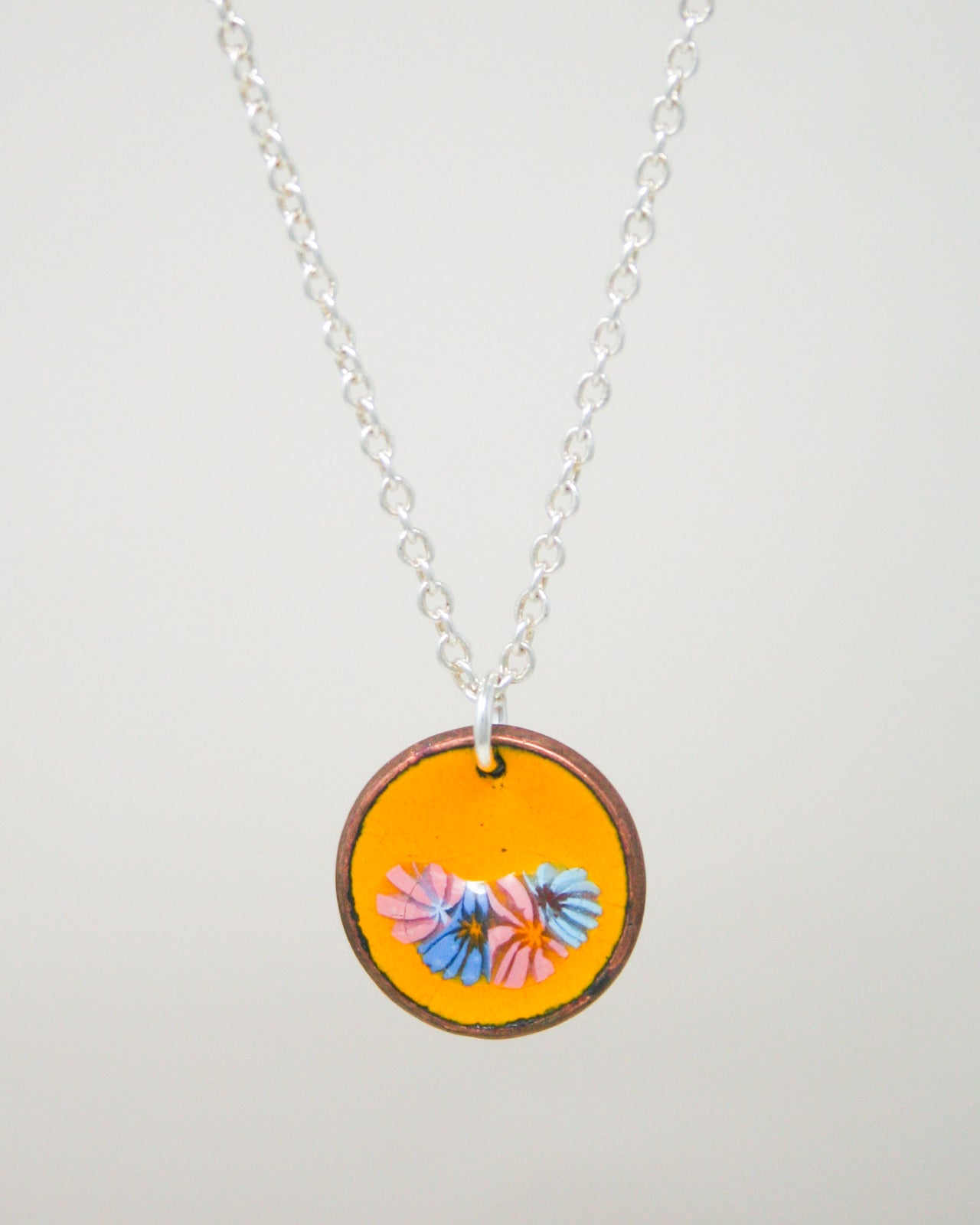 A necklace with a circular pendant featuring a vibrant design of colorful flowers.