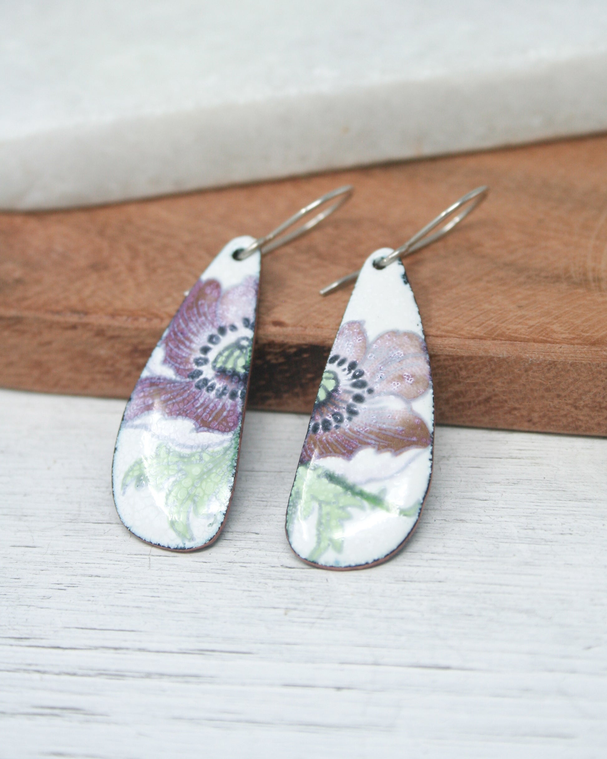 a pair of earrings sitting on top of a wooden board