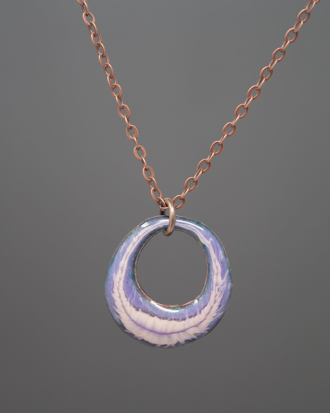 A necklace with a circular pendant featuring a blue and white swirl design.