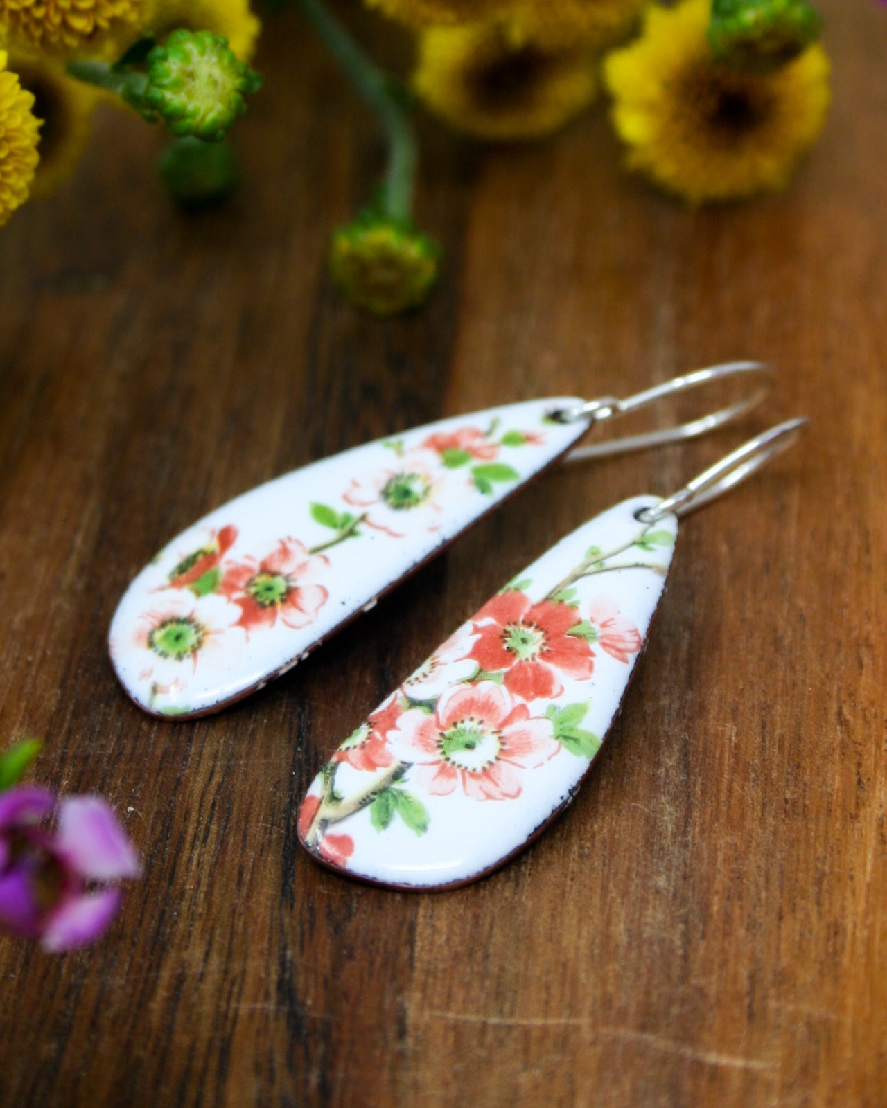 a pair of earrings with flowers painted on them