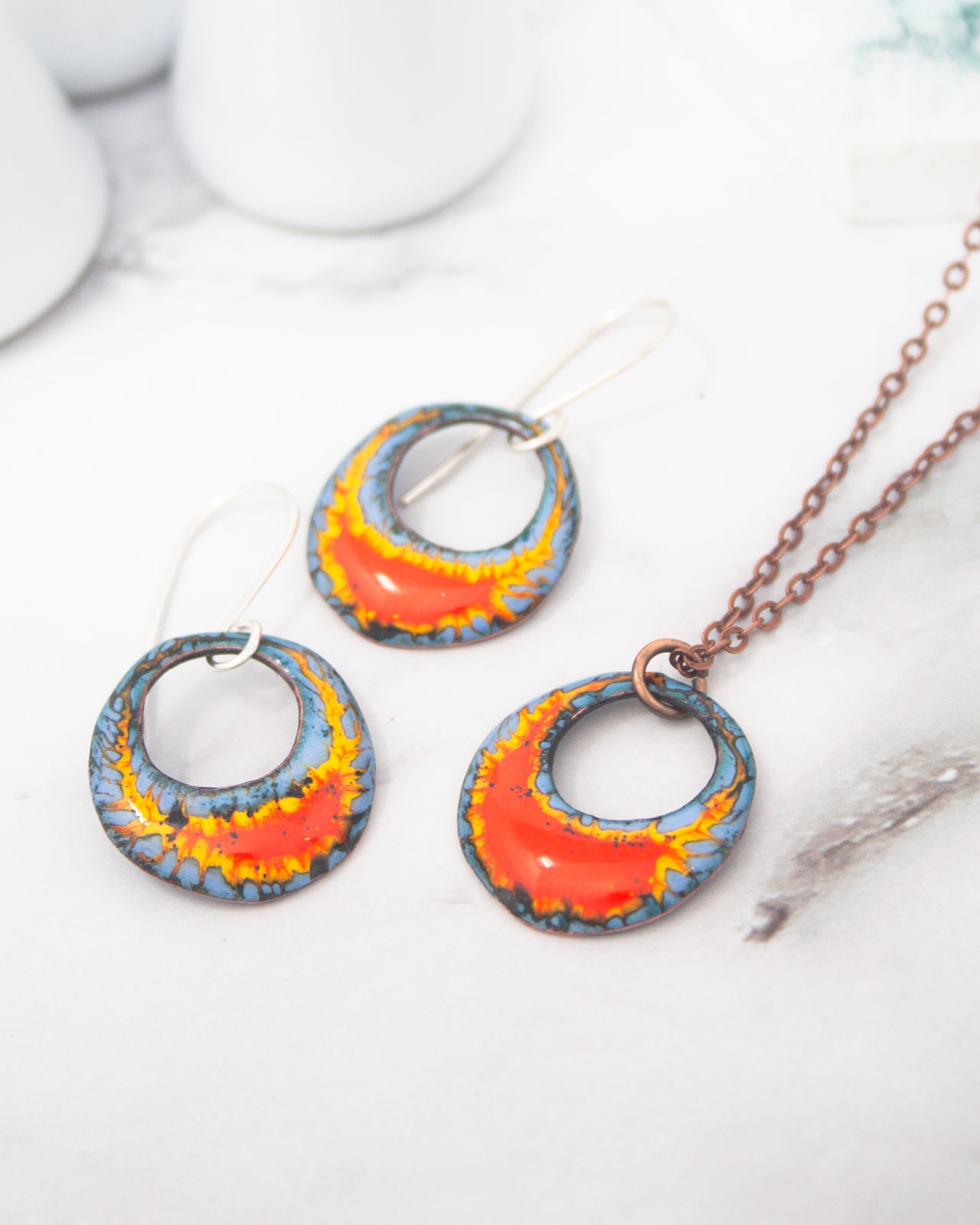 a pair of earrings and a necklace with colorful, abstract designs.