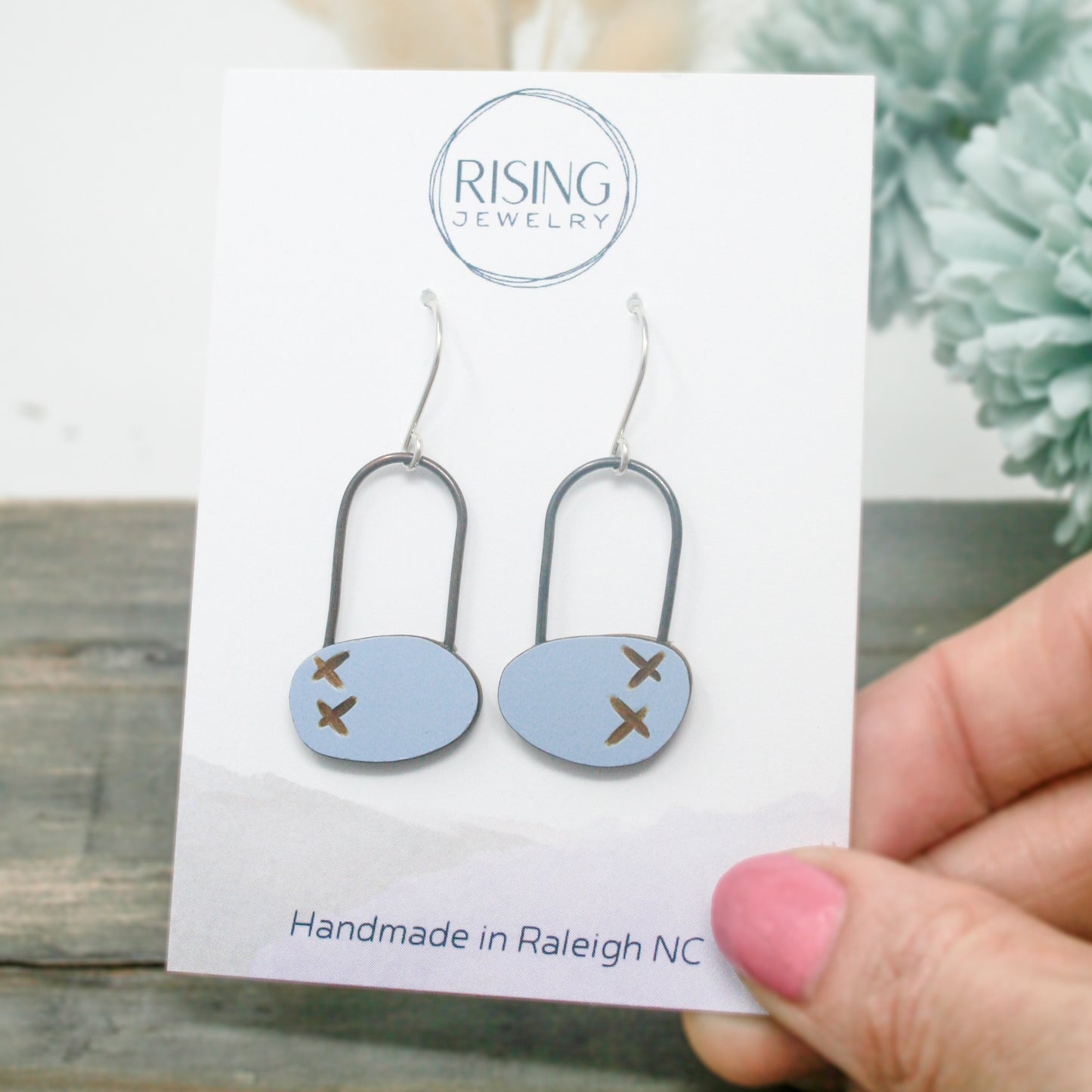 a pair of handmade earrings is displayed in front of a card