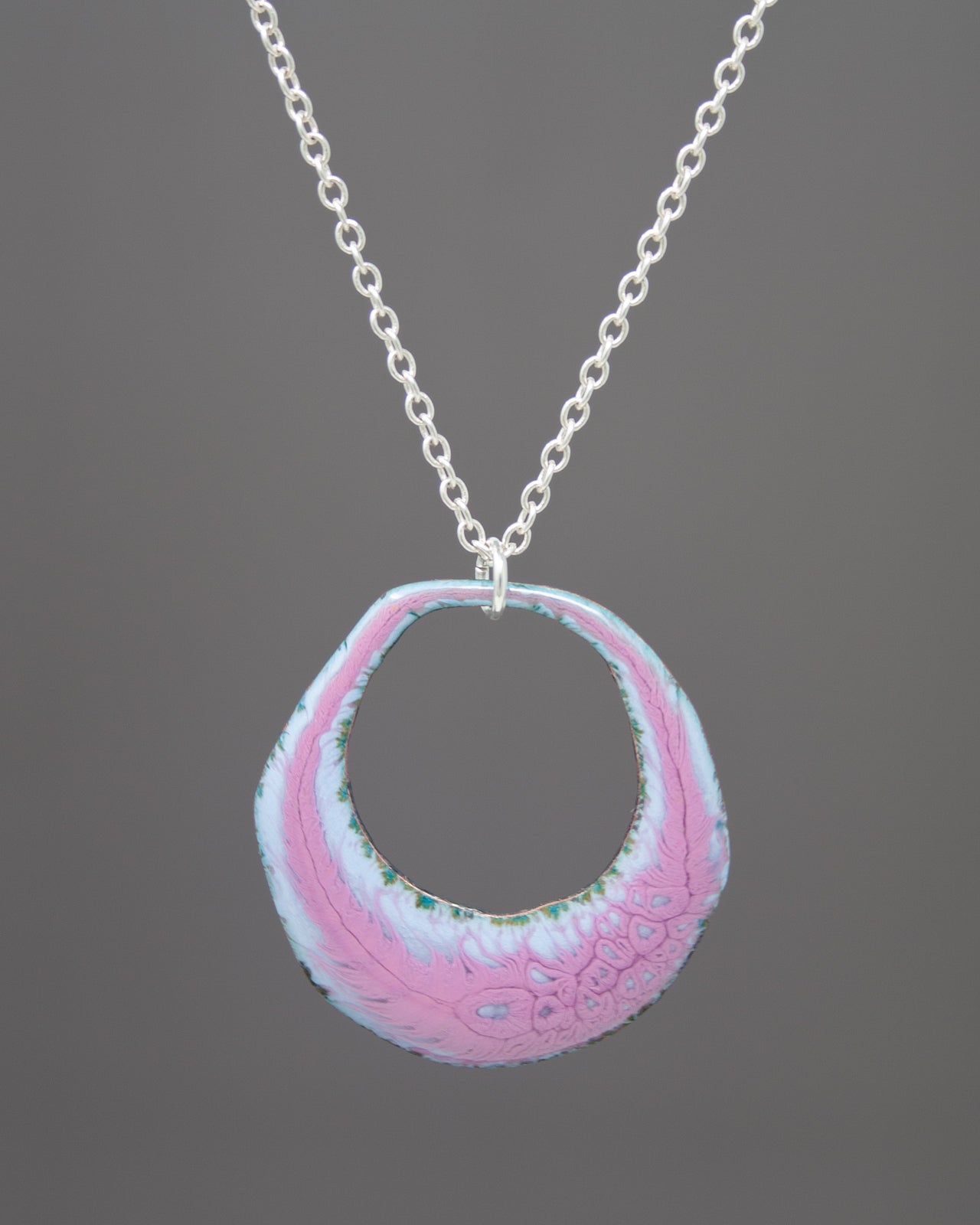 A necklace with a circular pendant featuring a pink and blue design.
