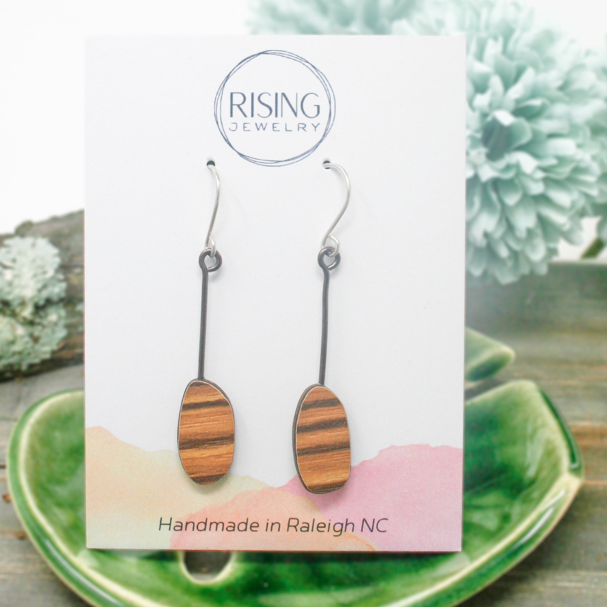 a pair of wooden earrings sitting on top of a green plate
