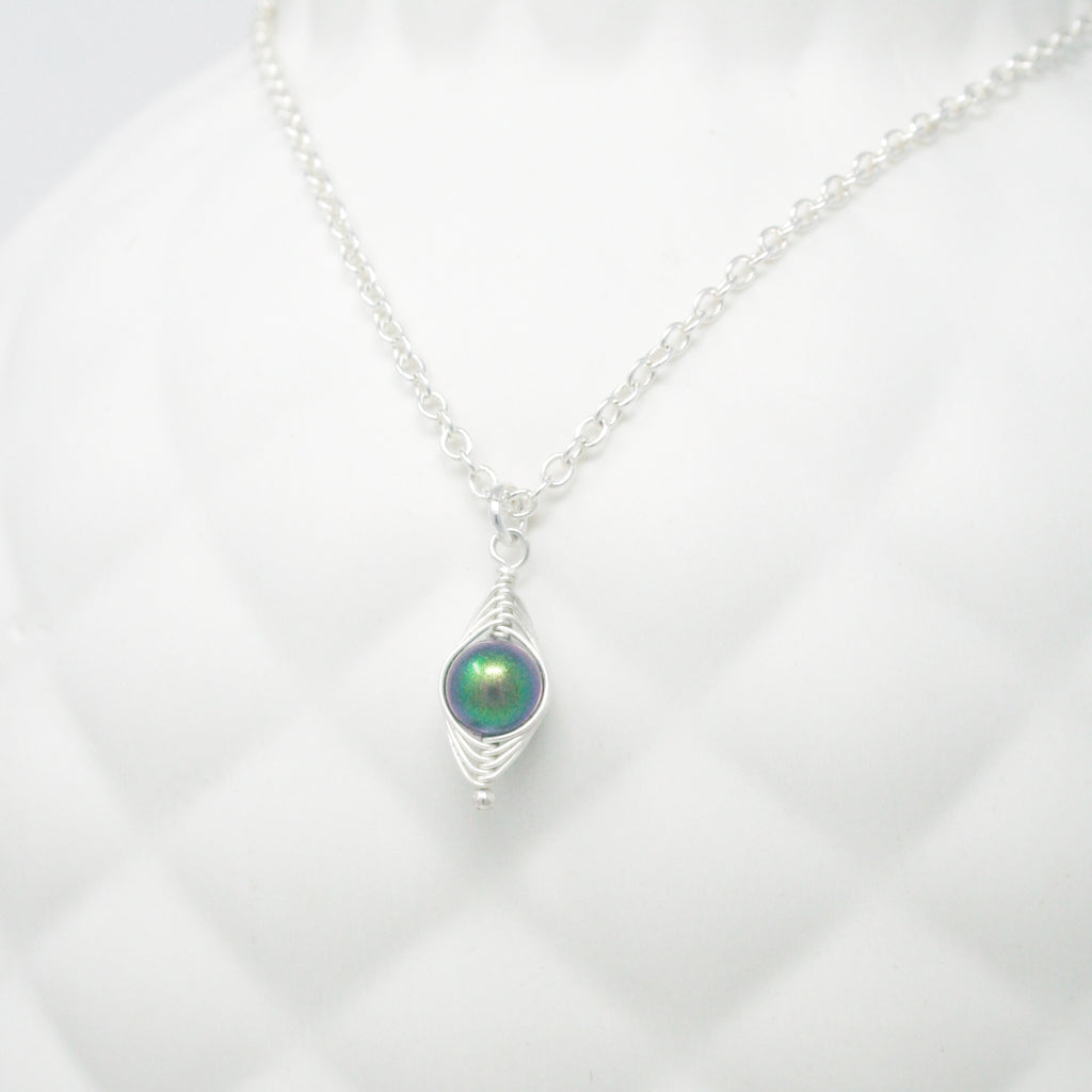 a silver necklace with a green pendant on a white background