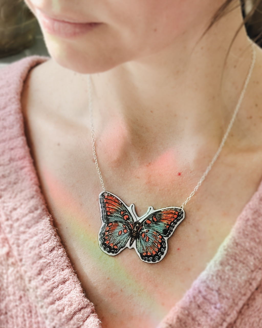 a woman wearing a necklace with a butterfly on it
