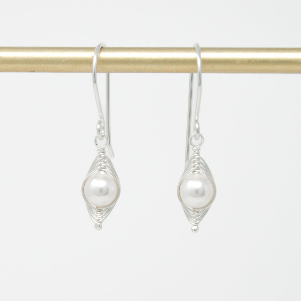 a pair of earrings hanging from a gold bar