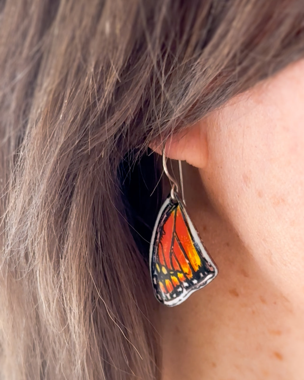 a close up of a person wearing a pair of earrings