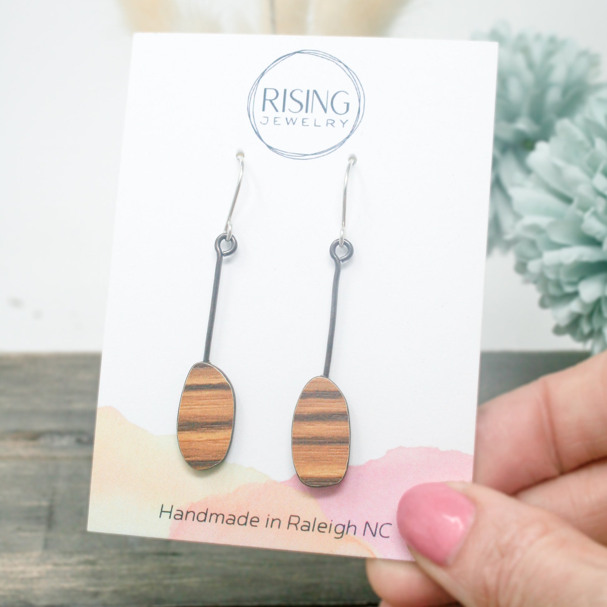 a pair of handmade wooden earrings on a card