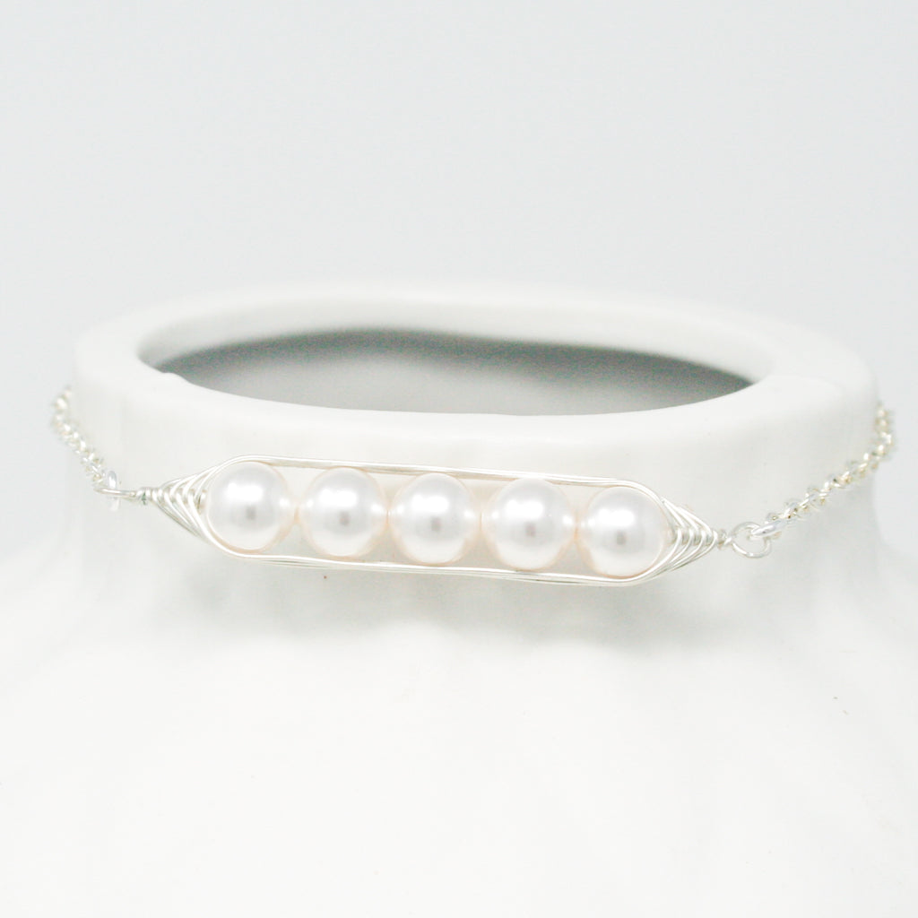 a white vase with three pearls attached to it