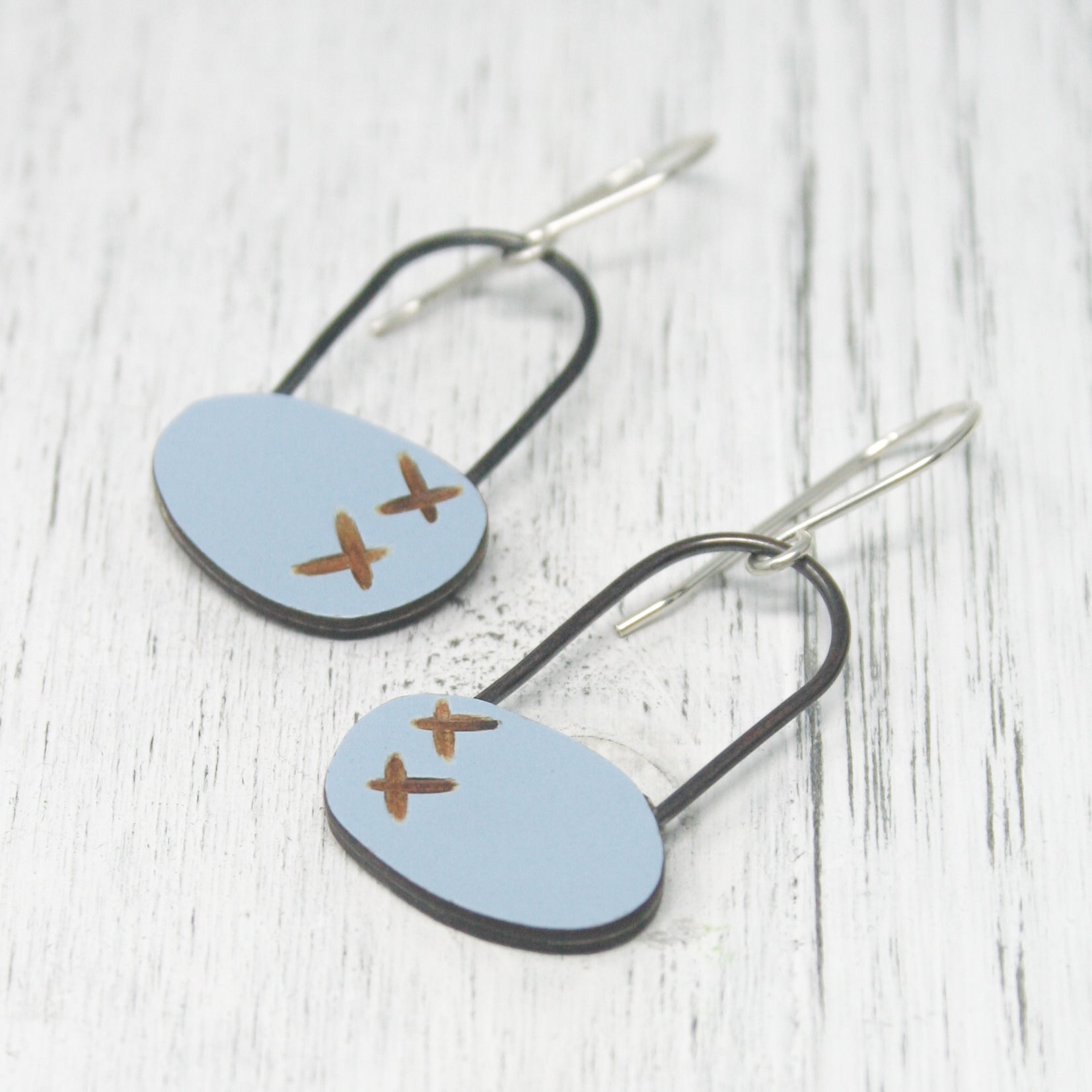 a pair of earrings with a plane painted on them