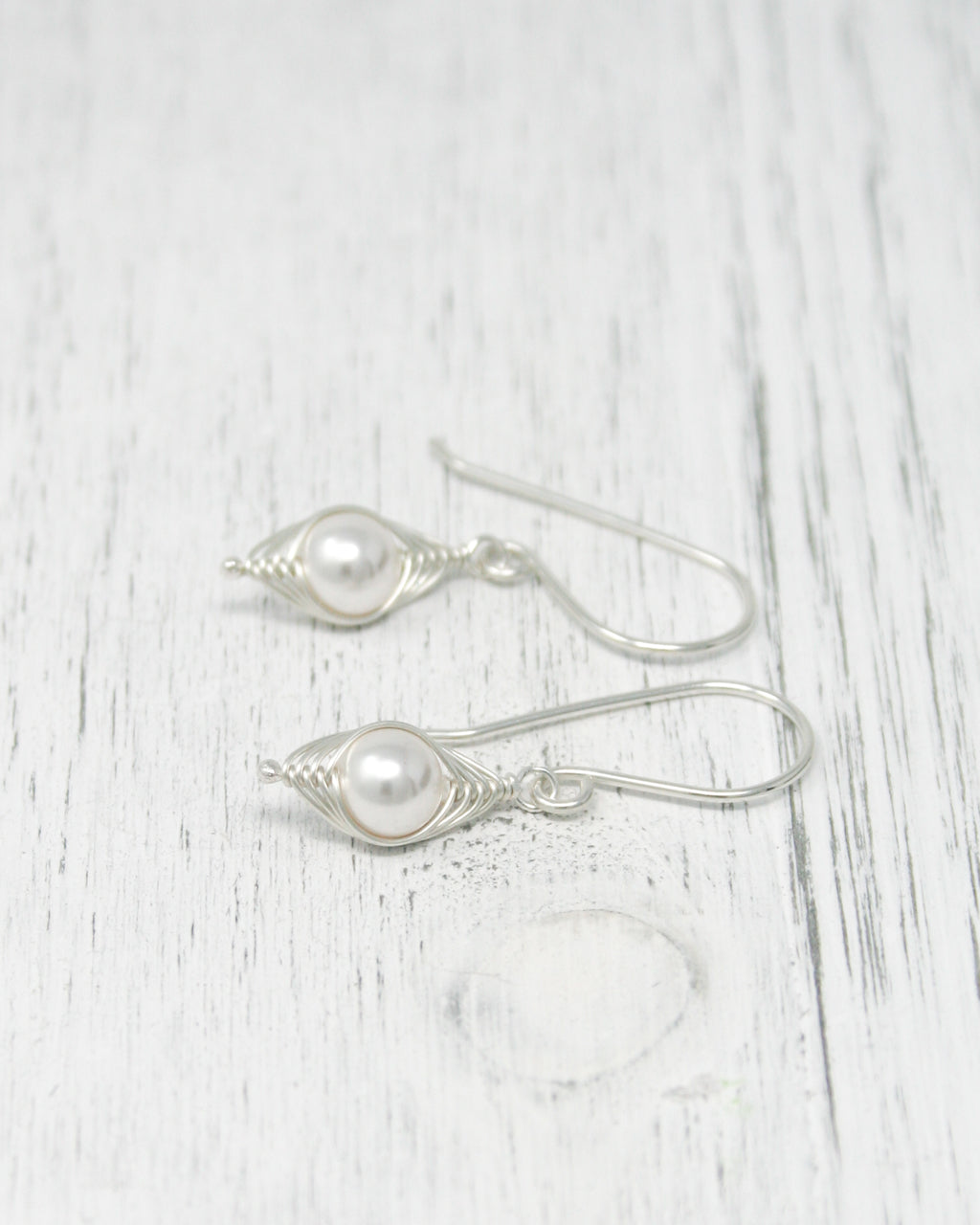 a pair of silver earrings with pearls on them