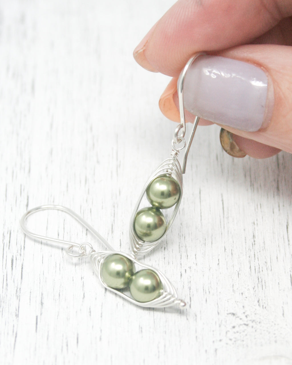 a person is holding a pair of earrings