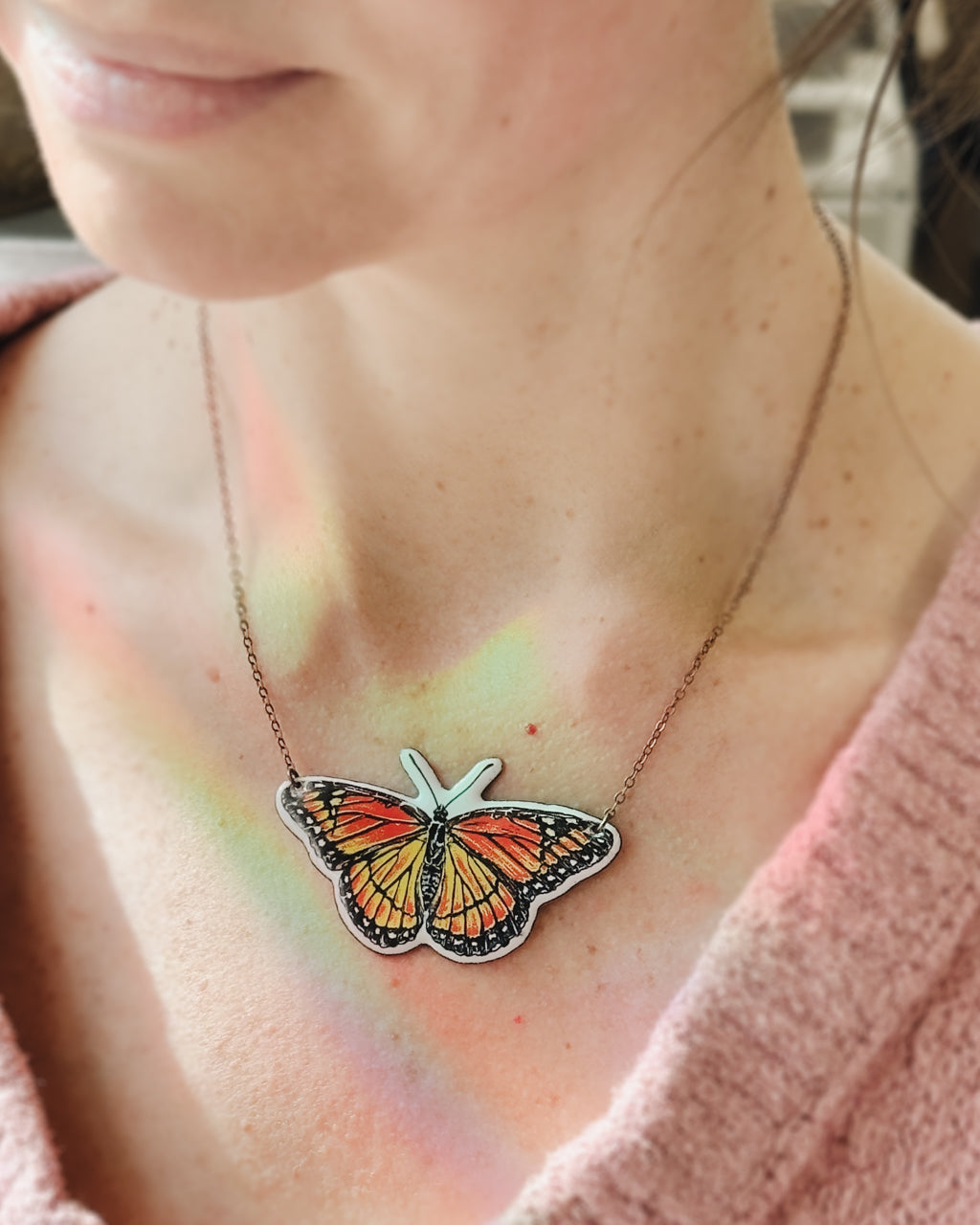 a woman wearing a necklace with a butterfly on it