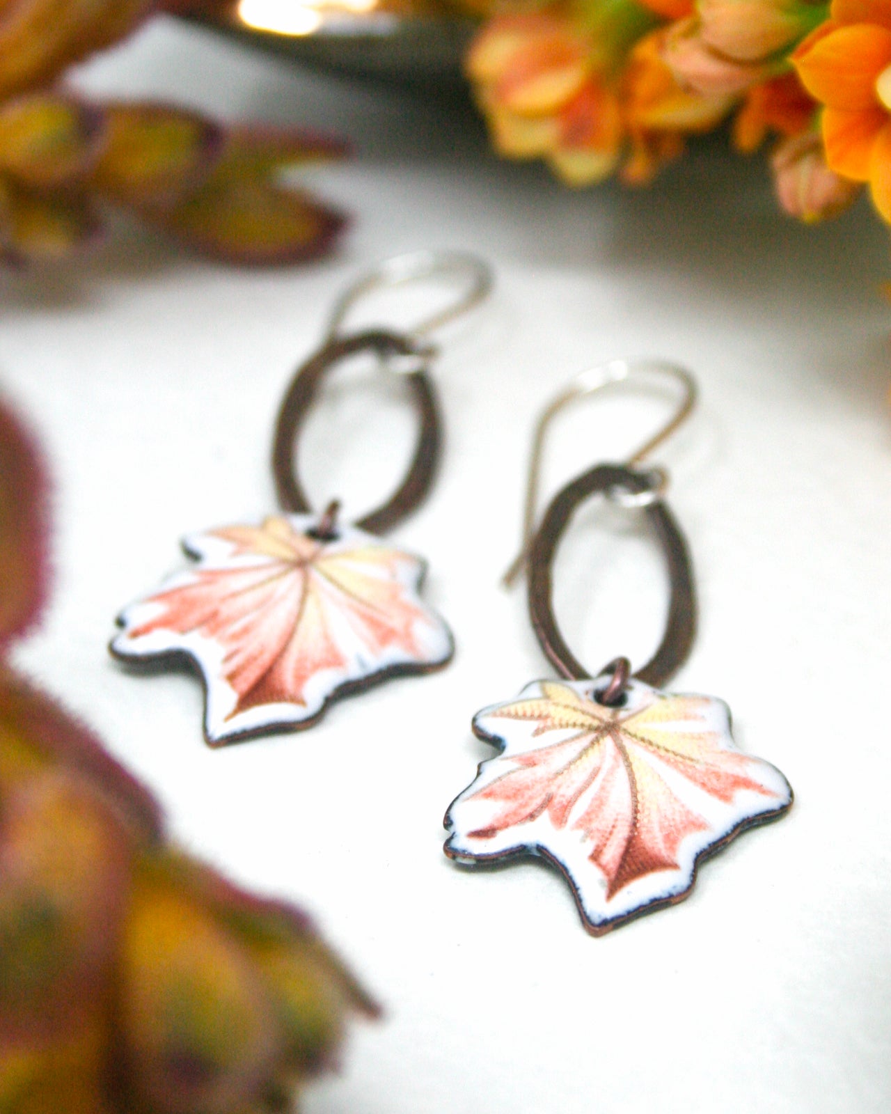 A pair of earrings with leaf-shaped designs, featuring a combination of pink and orange colors.