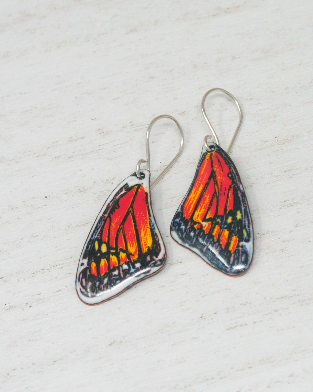a pair of orange and black butterfly earrings