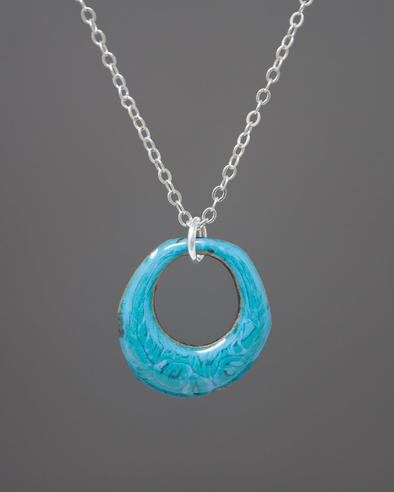A necklace with a blue oval pendant hanging from a silver chain.