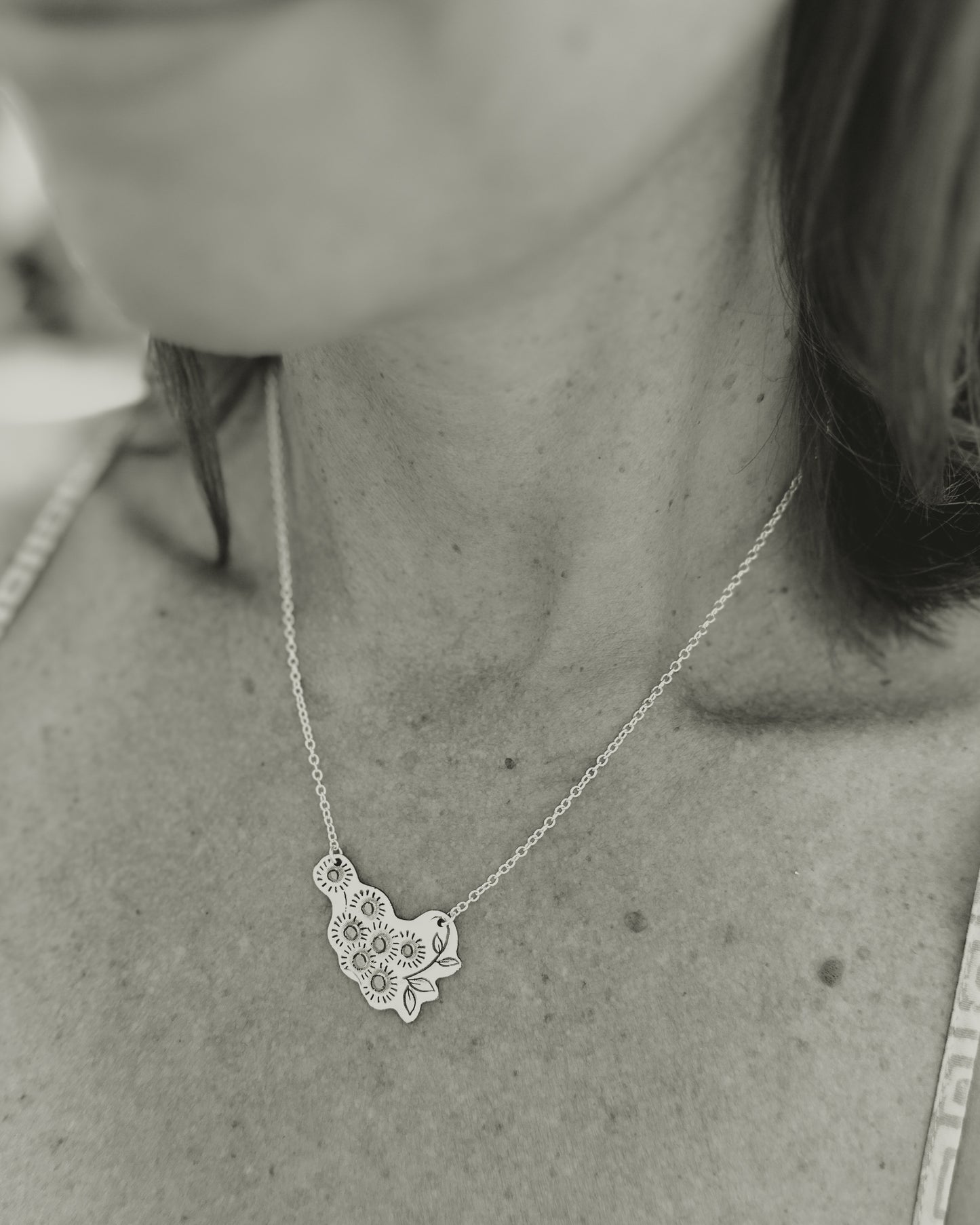 a black and white photo of a woman wearing a necklace
