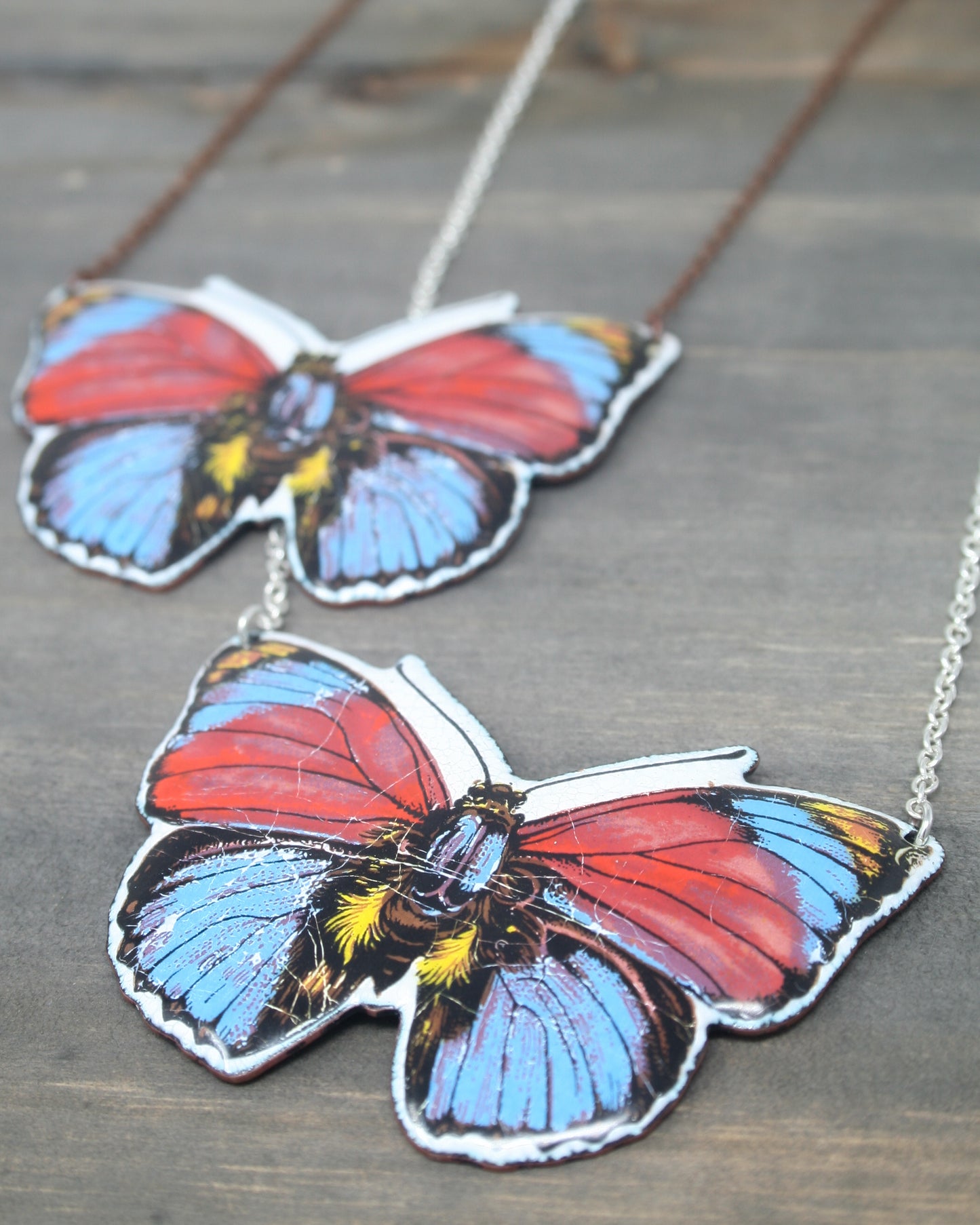 a couple of butterfly necklaces sitting on top of a wooden table