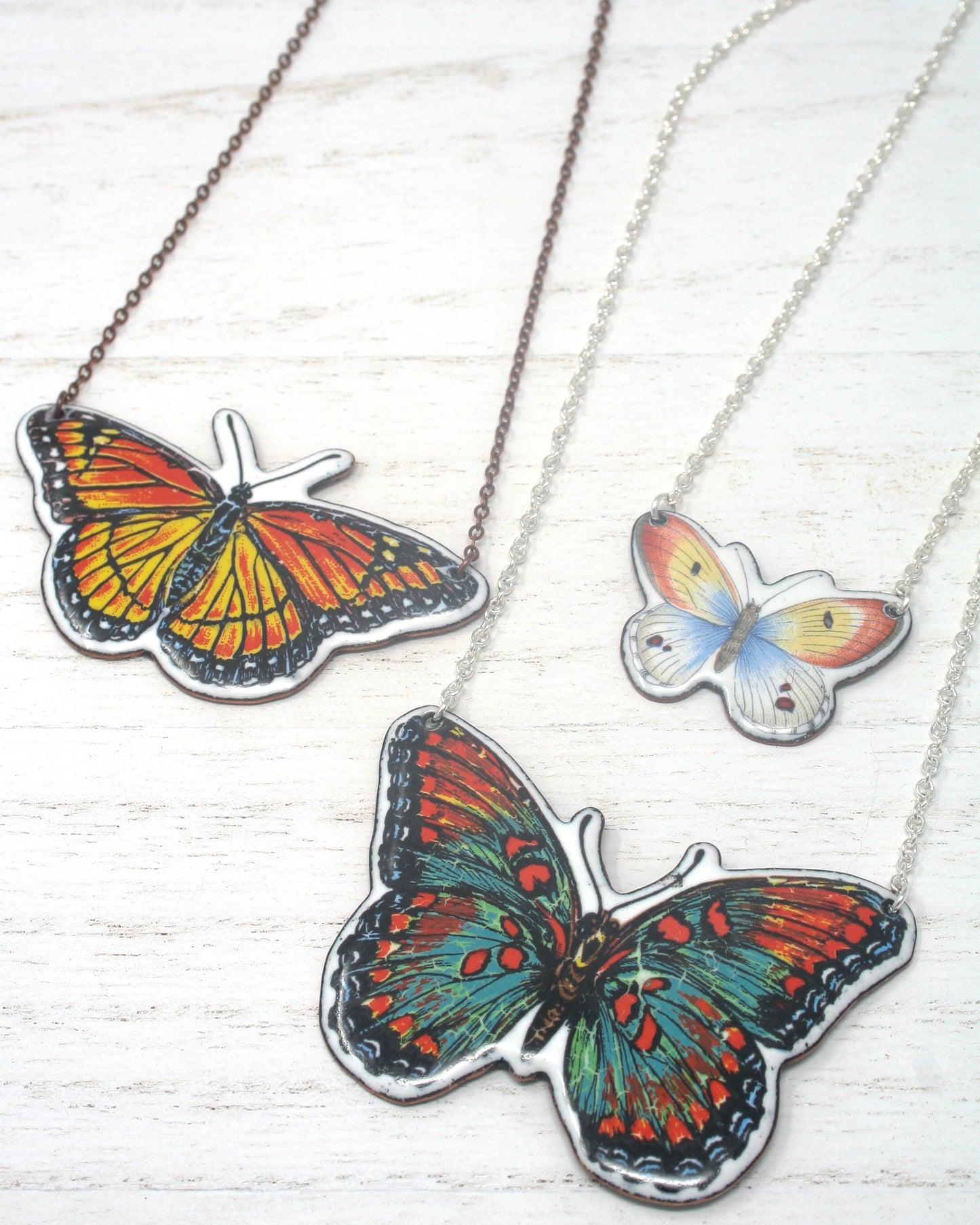 three butterfly pendants on a chain on a table