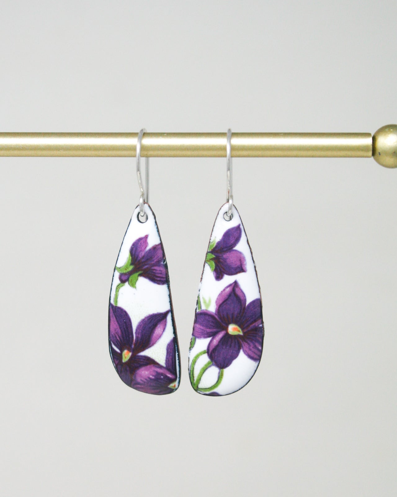 a pair of earrings with purple flowers on them