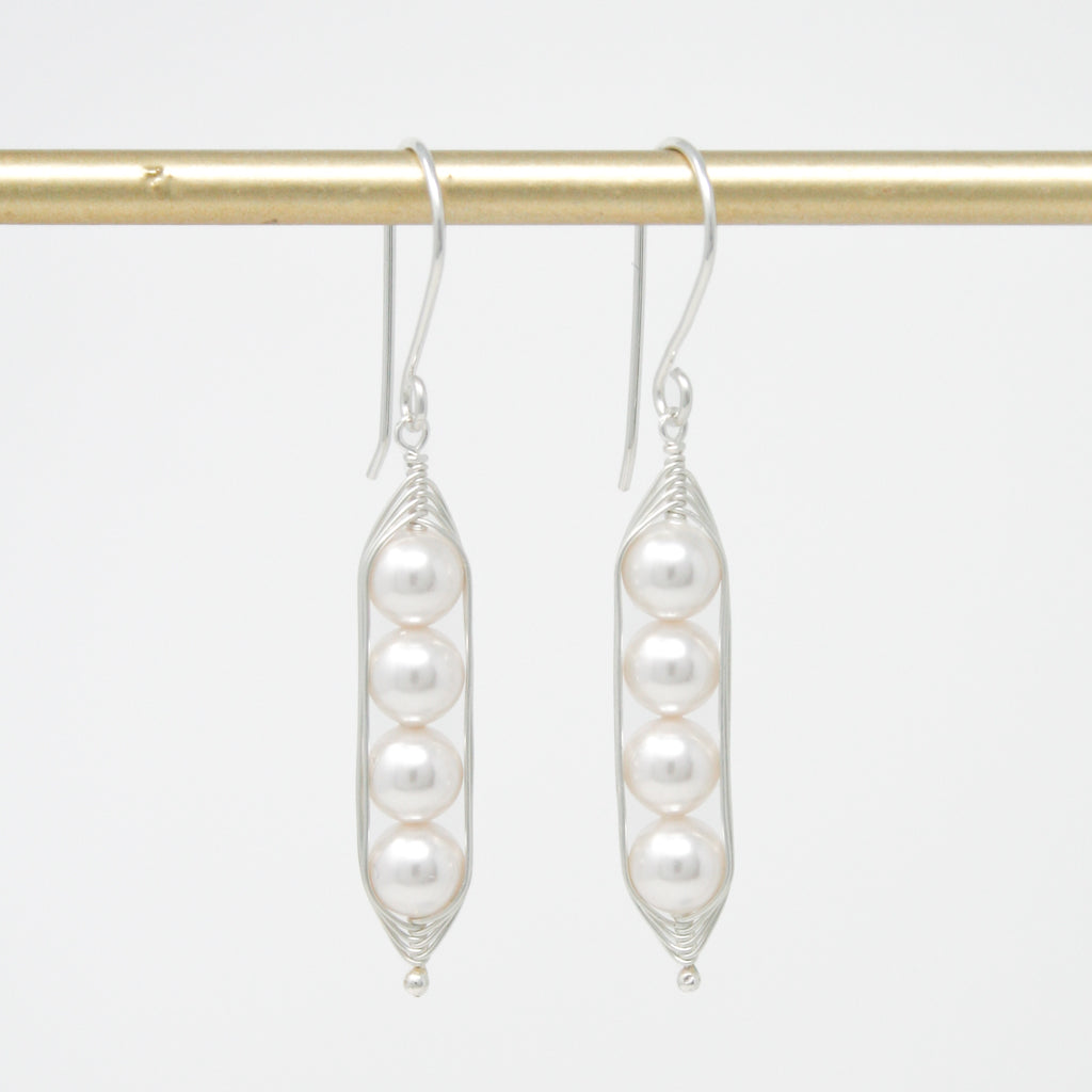 a pair of earrings with pearls hanging from them
