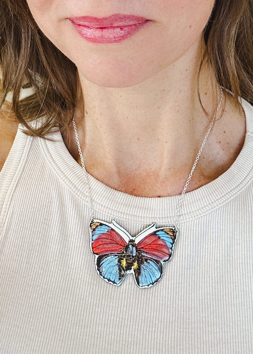 a woman wearing a necklace with a butterfly on it
