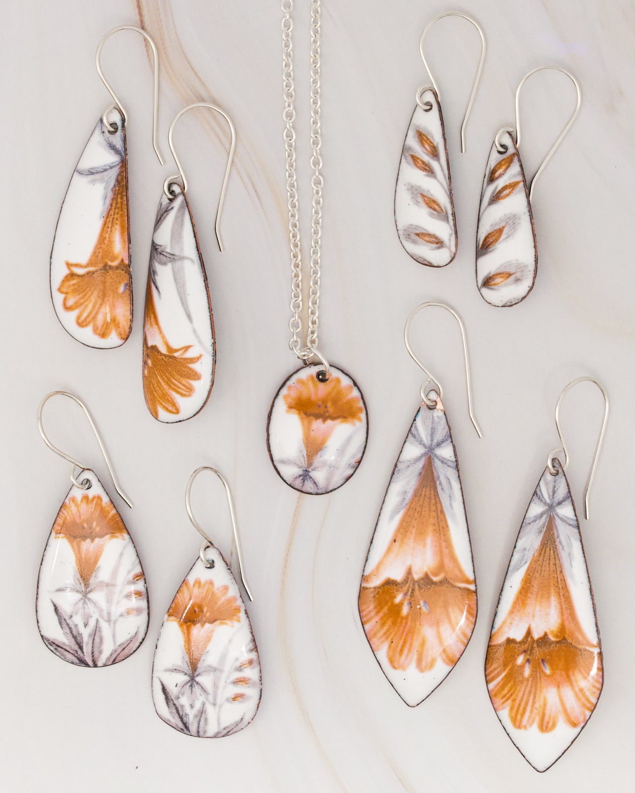 a collection of earrings and a necklace featuring floral designs in shades of orange and white.