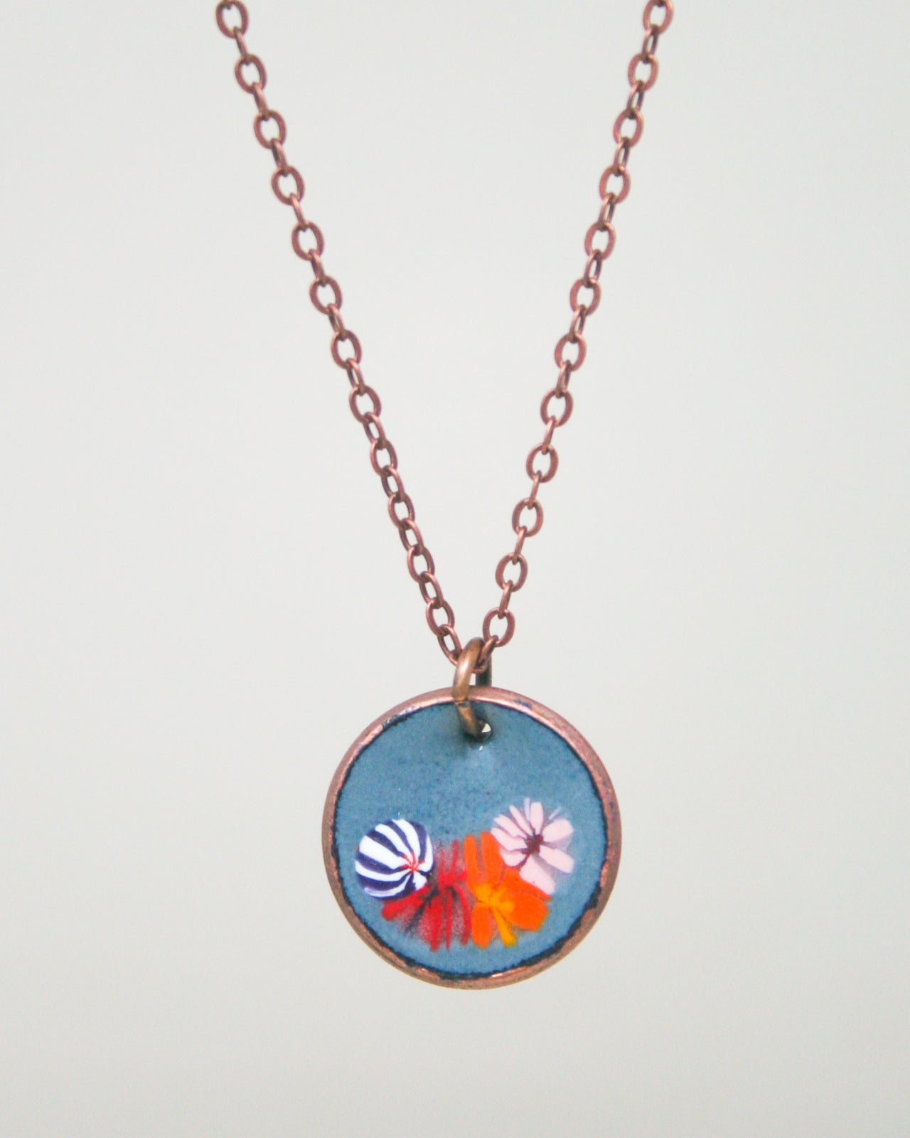 A necklace with a circular pendant featuring a colorful floral design.