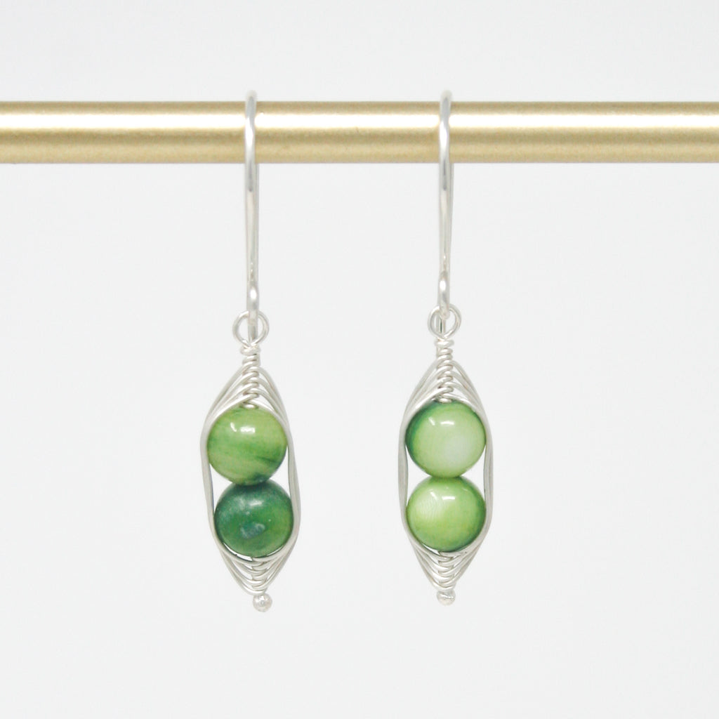 a pair of earrings with green beads hanging from a hook