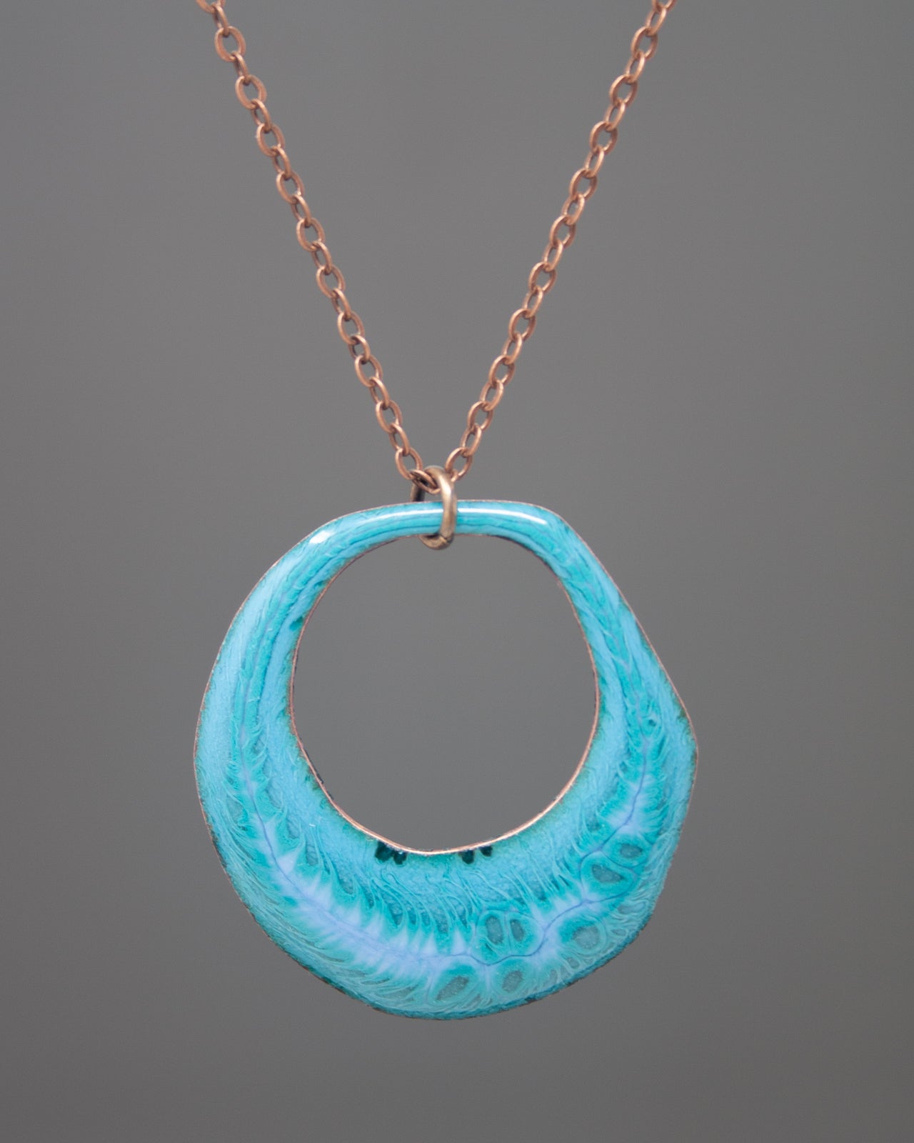 A necklace with a blue-green pendant hanging from a chain.