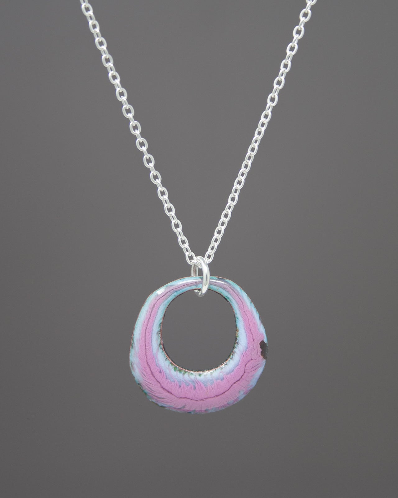 A necklace with a circular pendant in shades of pink and blue.