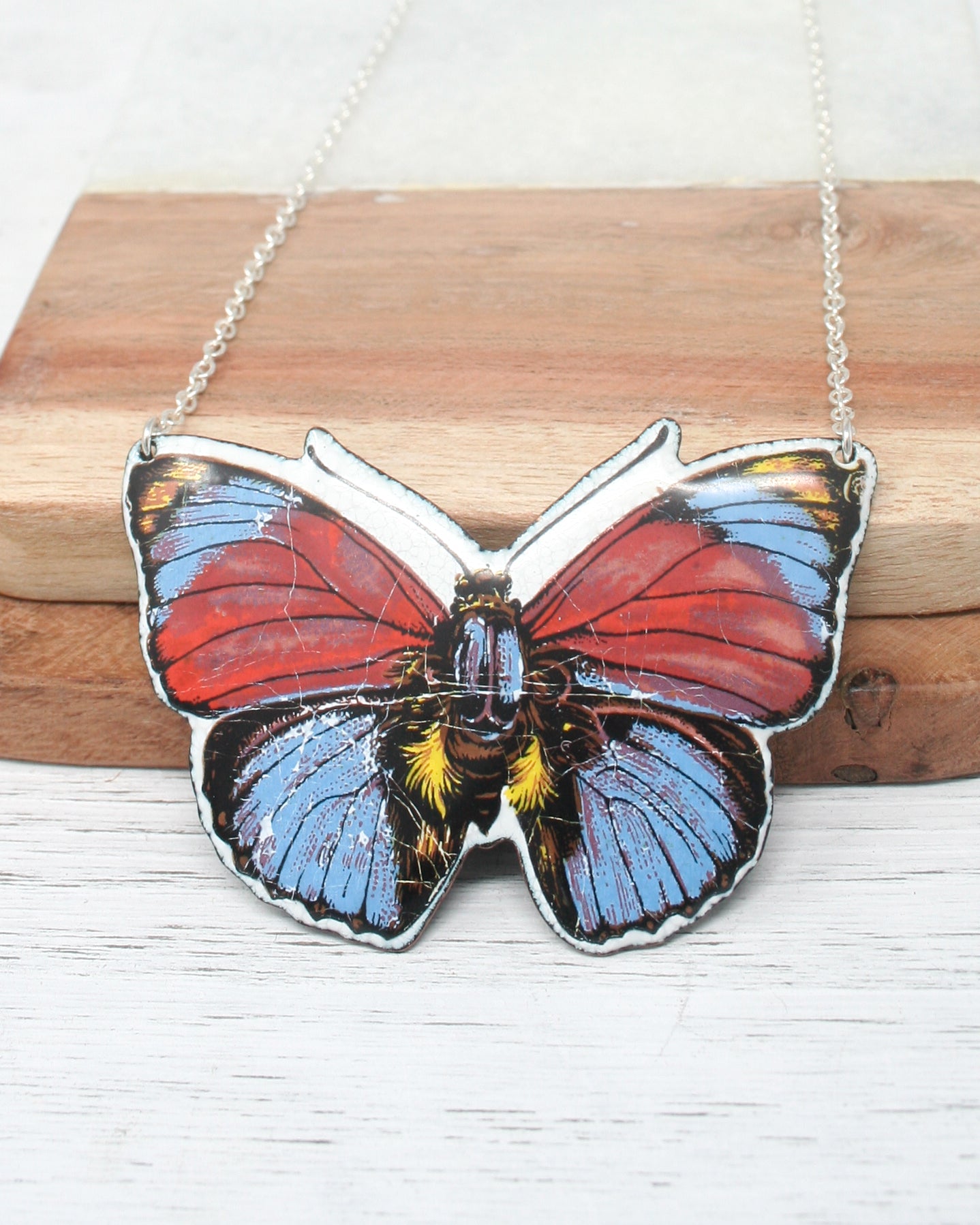 a red, white and blue butterfly on a chain