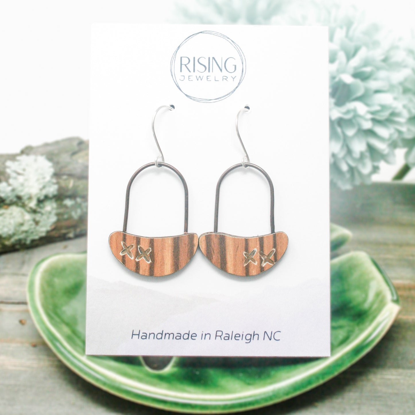 a pair of wooden earrings sitting on top of a green plate