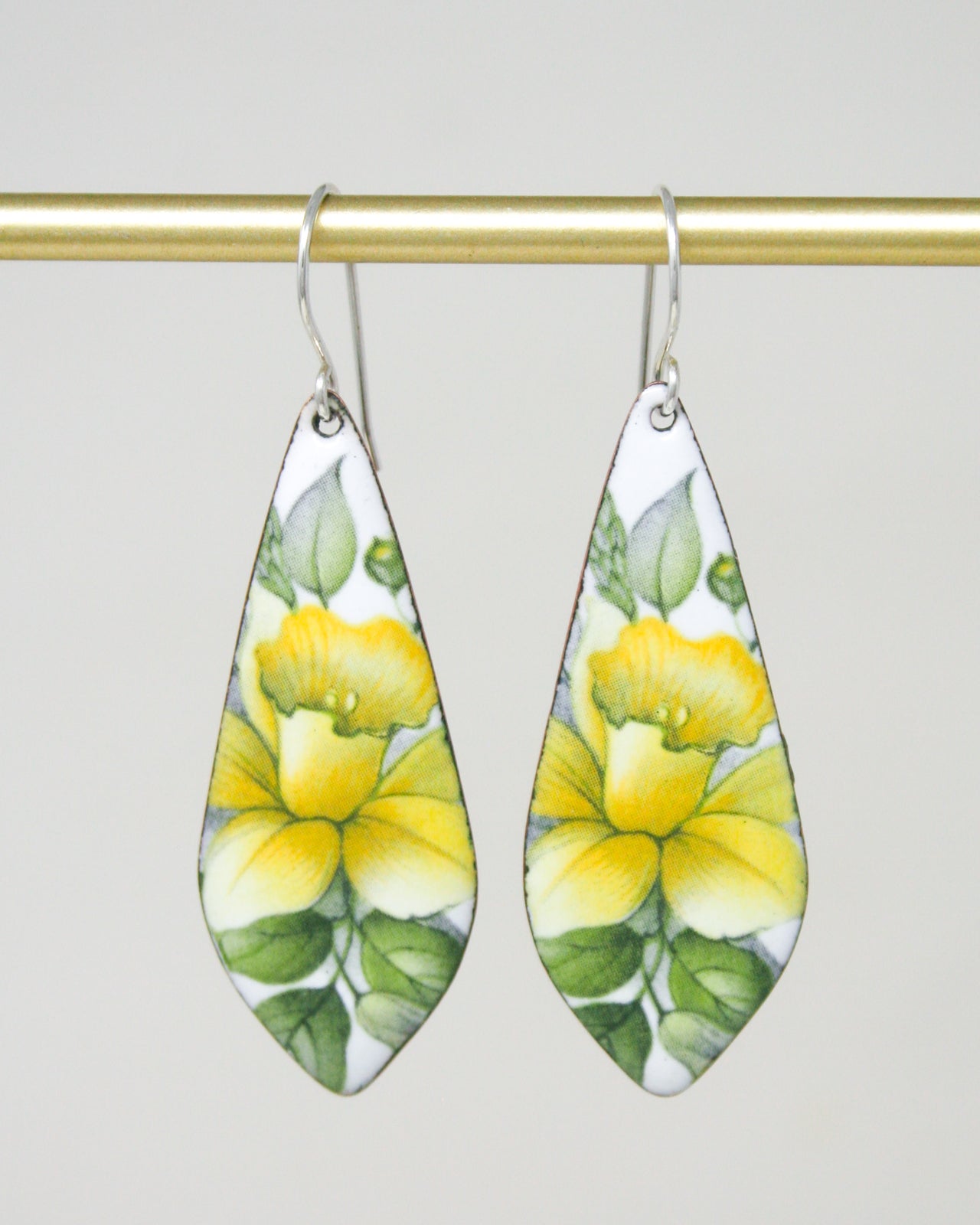 a pair of earrings with yellow flowers painted on them