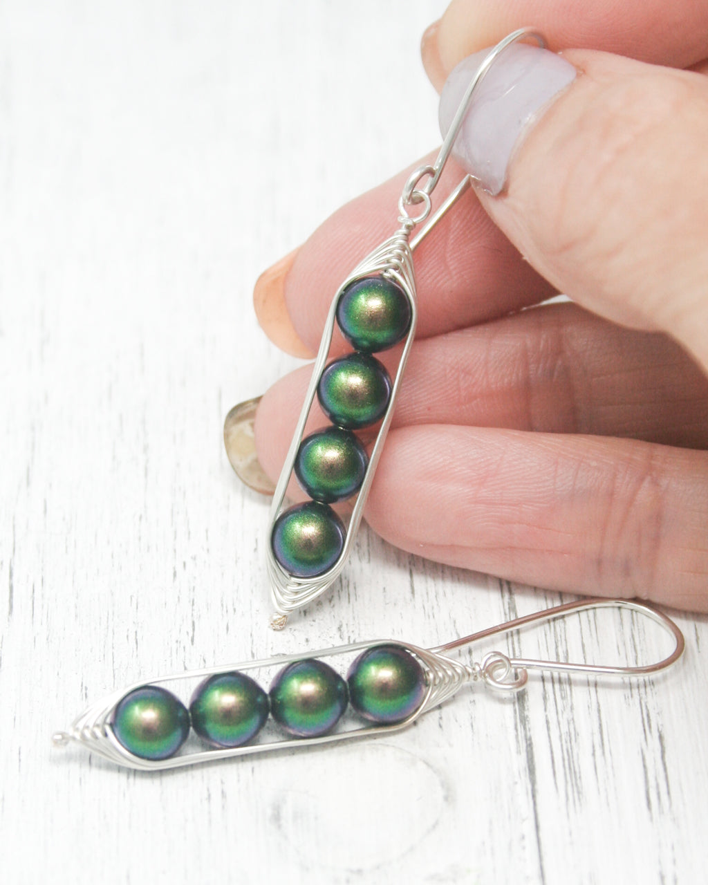 a person is holding a pair of earrings