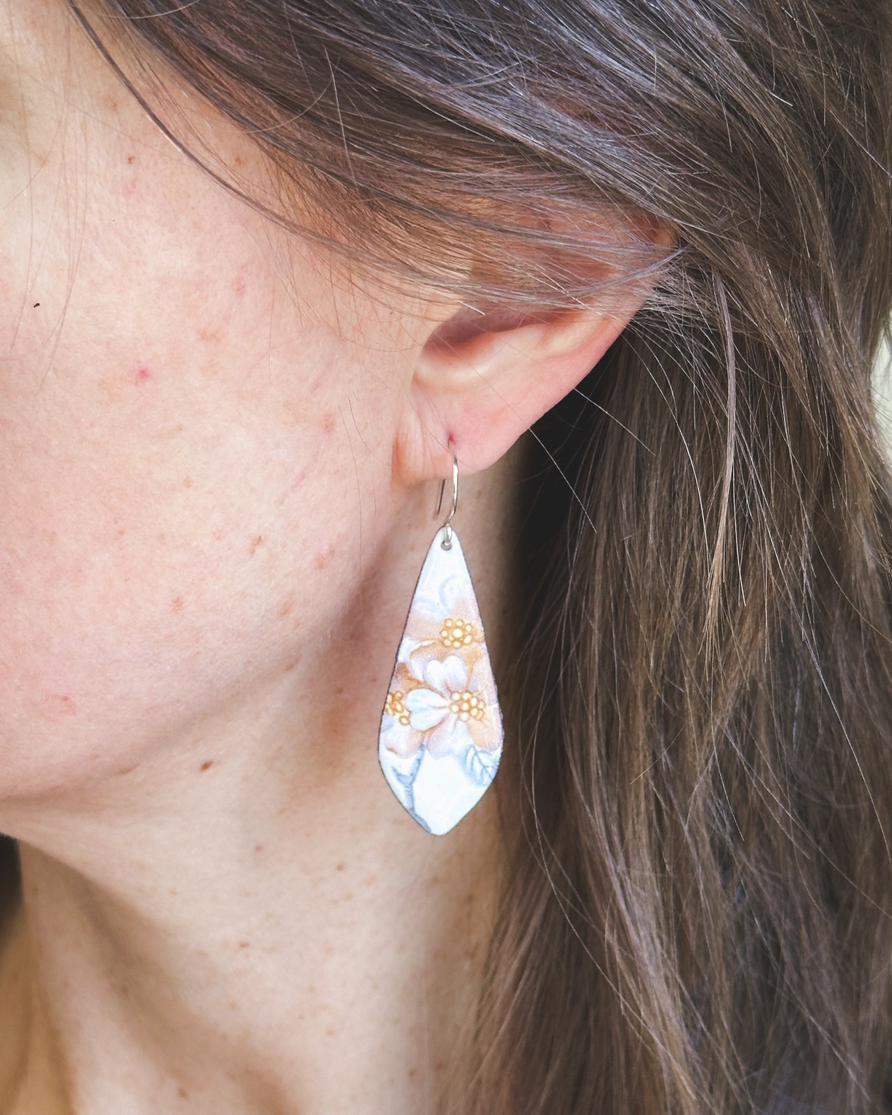 a close up of a person wearing a pair of earrings