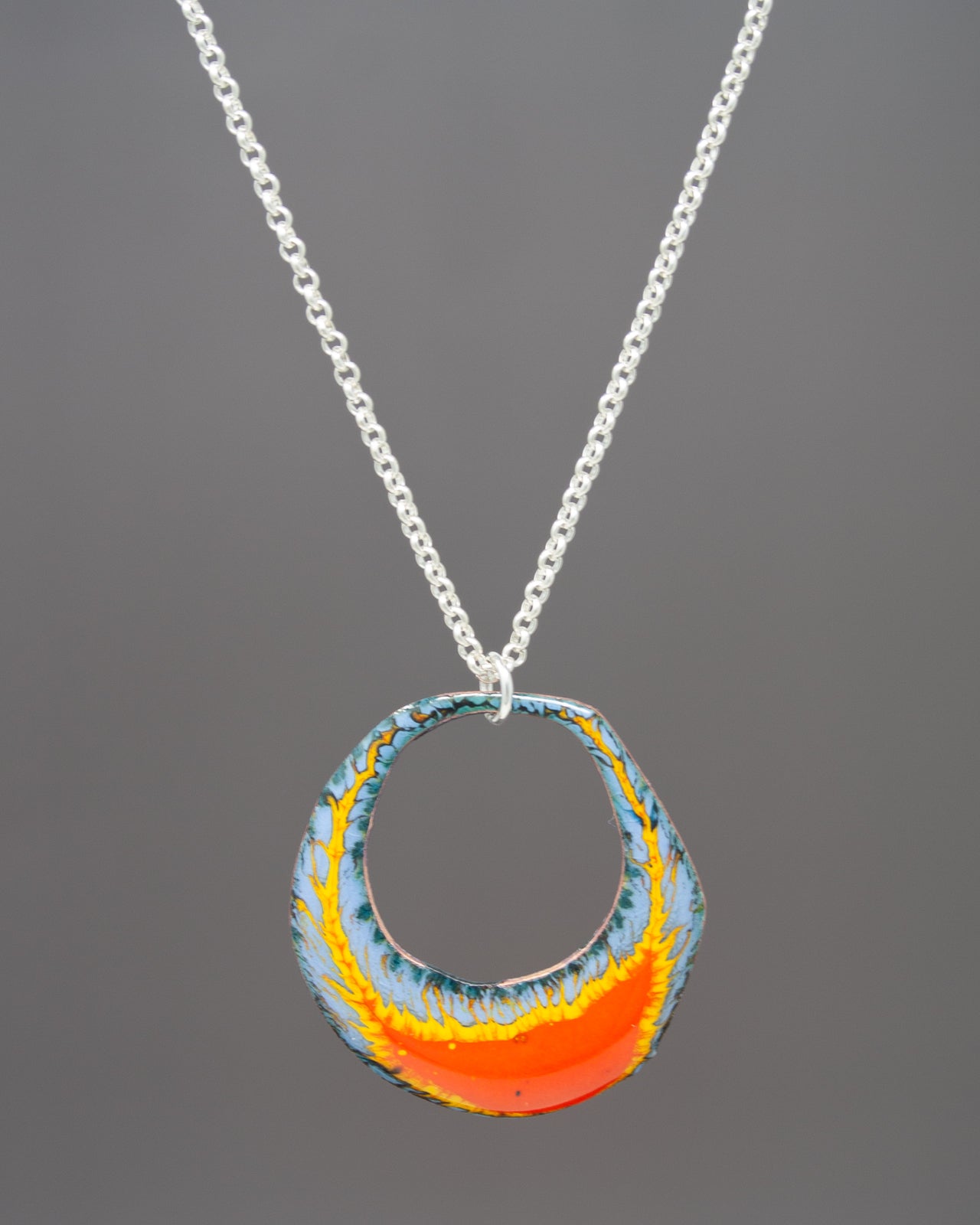 A colorful pendant necklace with a circular design featuring a vibrant mix of orange, blue, and yellow colors.