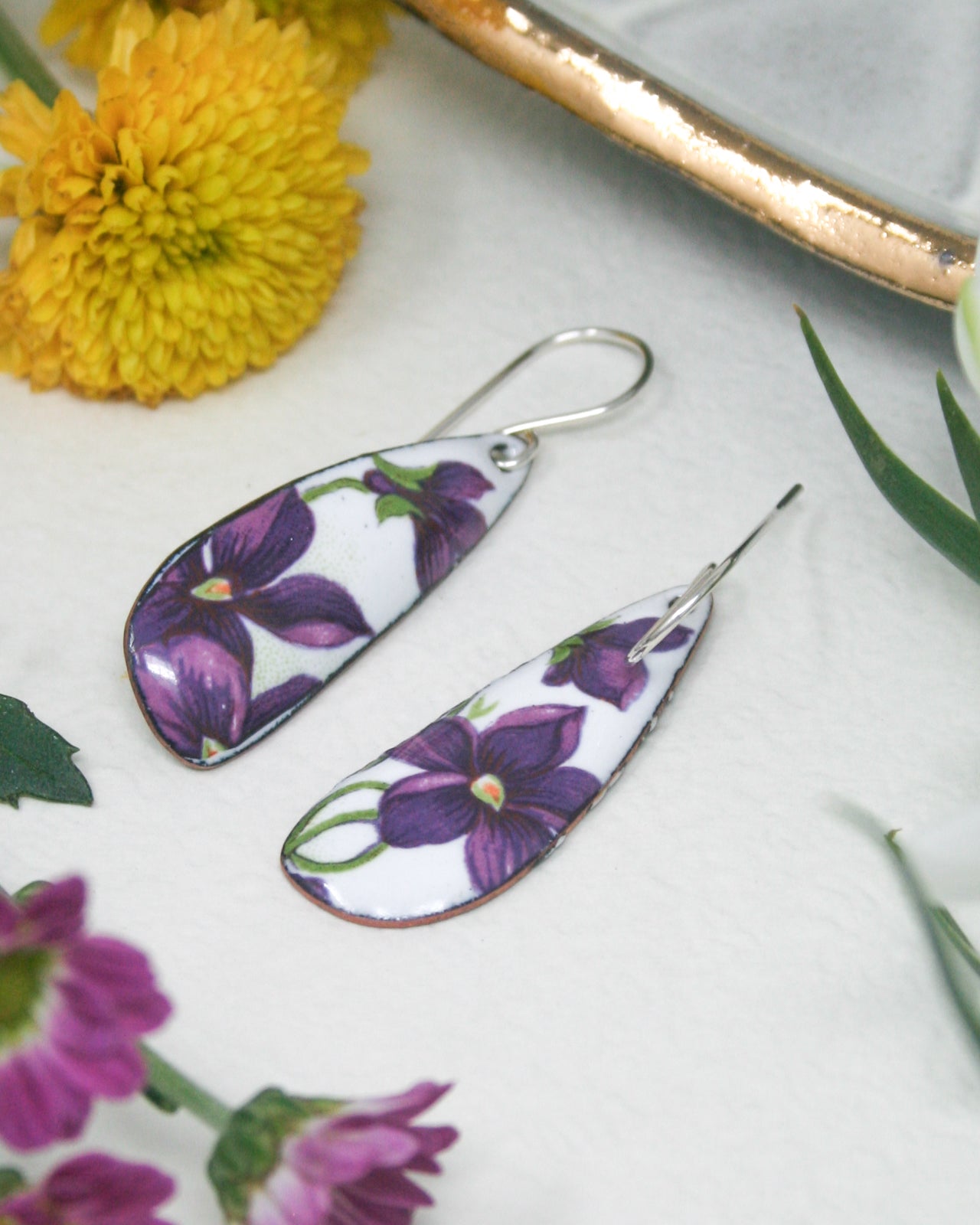 a pair of earrings with purple flowers on them