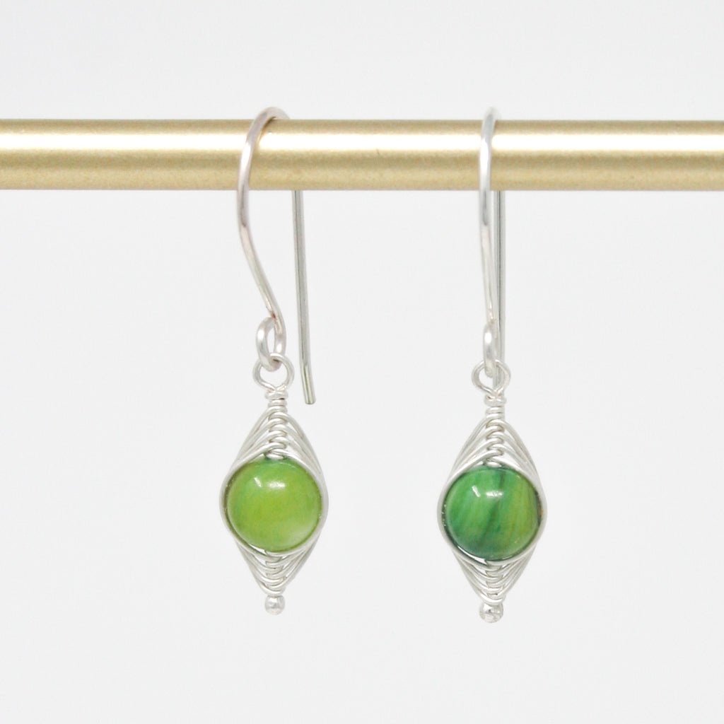 a pair of green earrings hanging from a hook