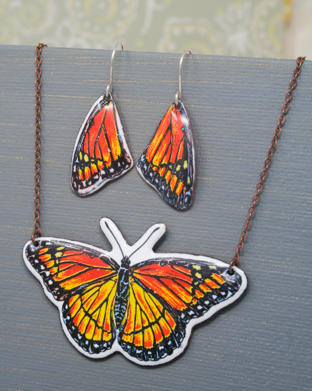 a necklace and earrings with a picture of a butterfly on it