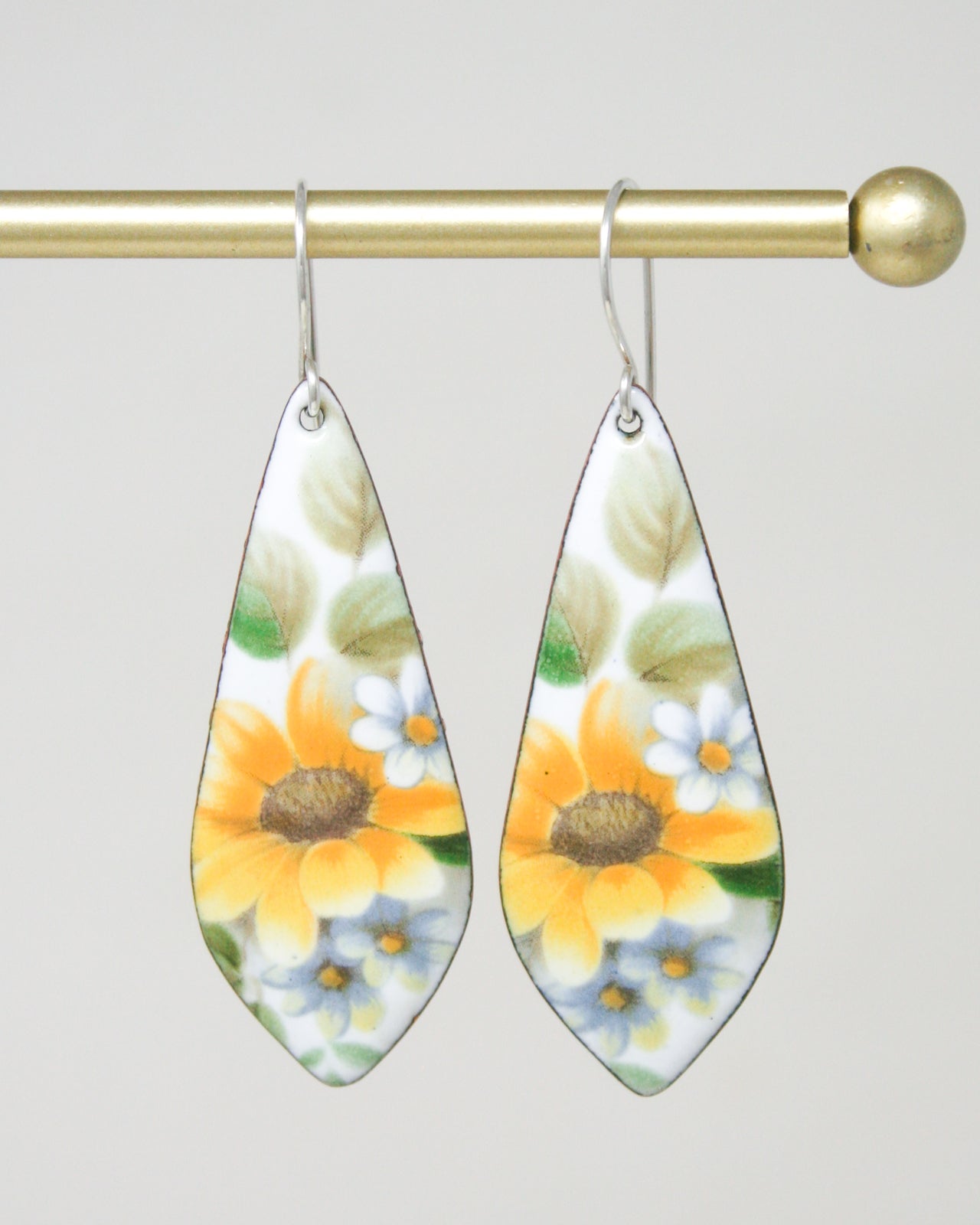 a pair of earrings hanging from a metal rod