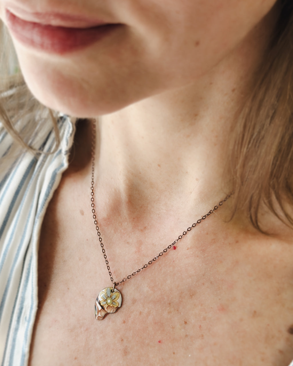 A close-up of a woman's neck and chest area, showing a delicate necklace with a pendant.