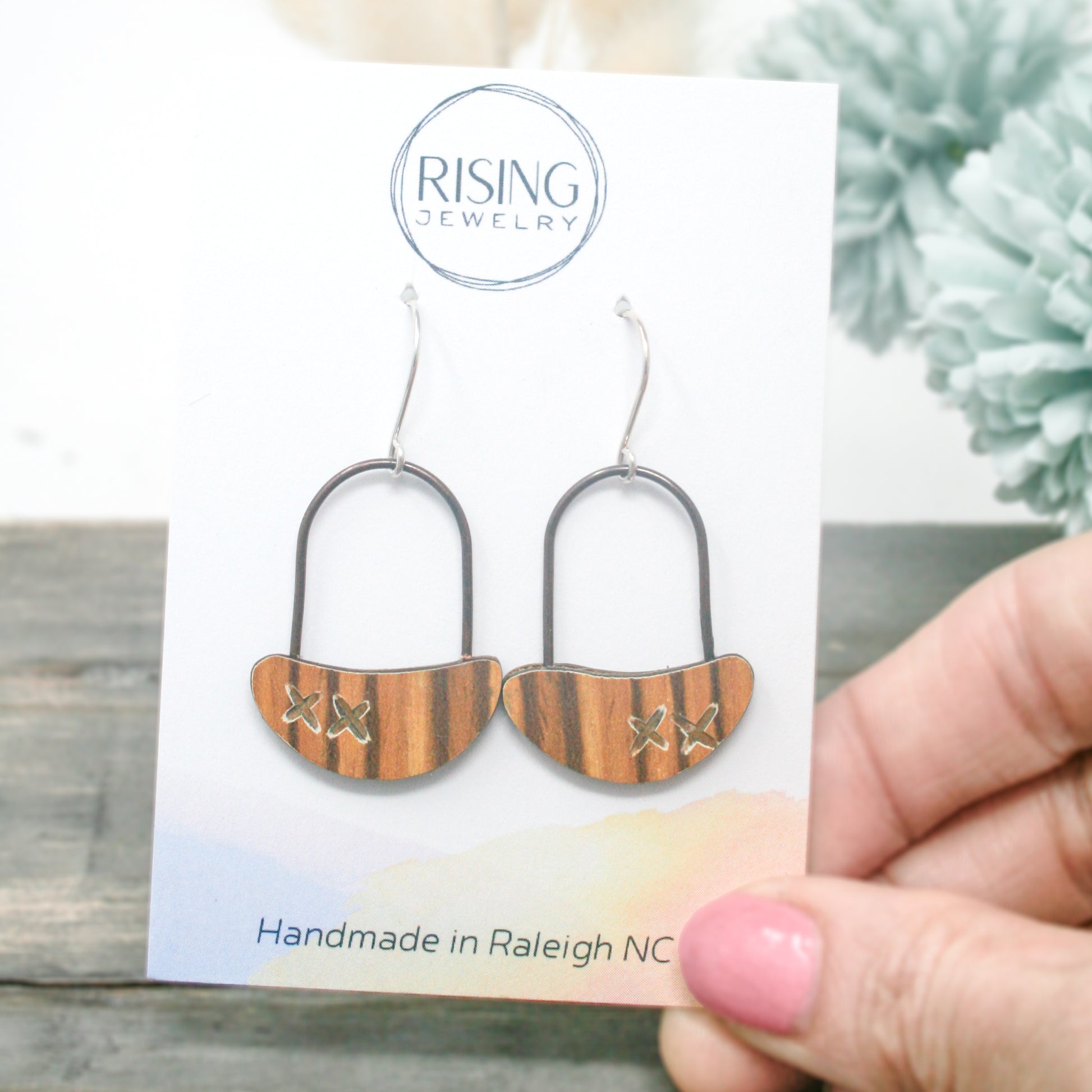 a pair of handmade wooden earrings on a card